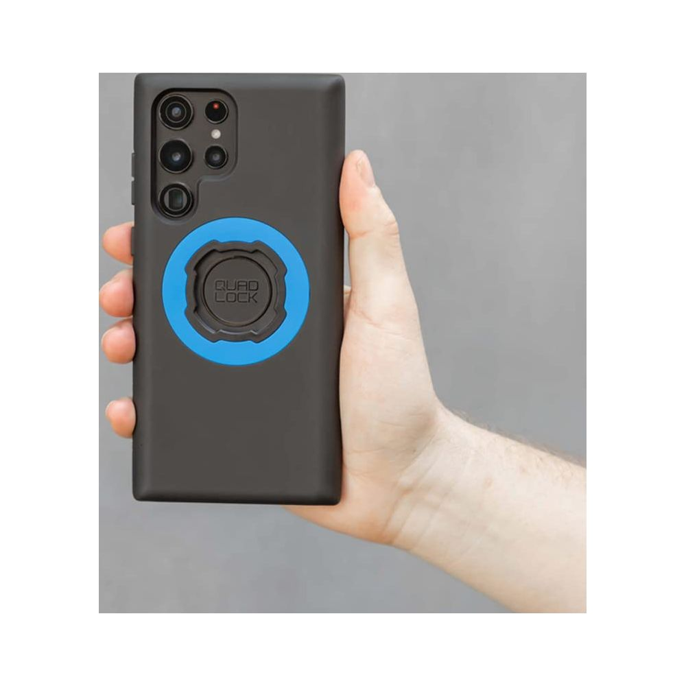 Eine Hand hält ein schwarzes Smartphone mit einer blauen Quad Lock-Halterung.