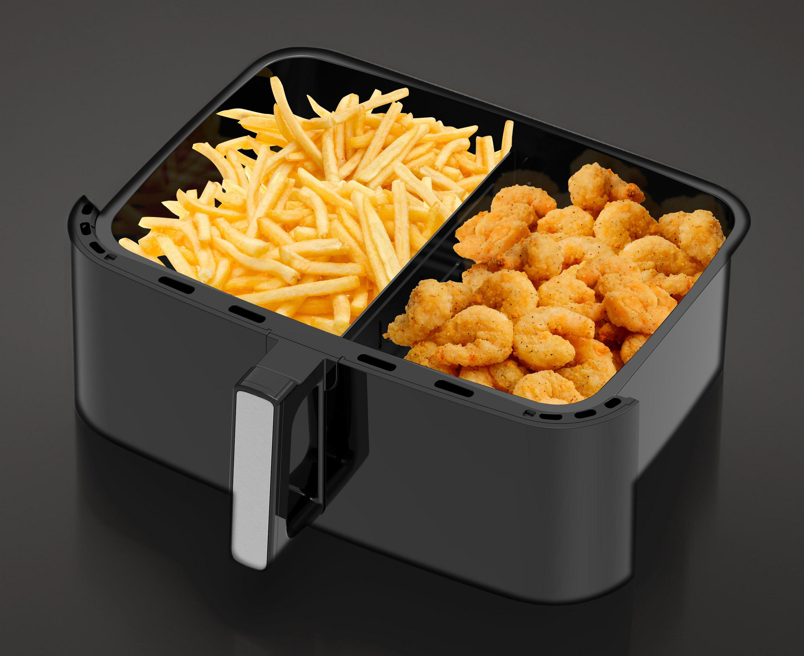 Ein schwarzer Airfryer mit zwei Fächern gefüllt mit Pommes und Garnelen.