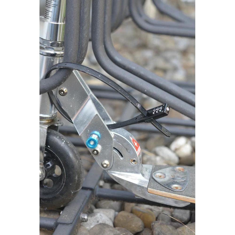 Ein silberner Roller-Mechanismus mit schwarzem Kabelbinder, der an dunklen Rohren befestigt ist.