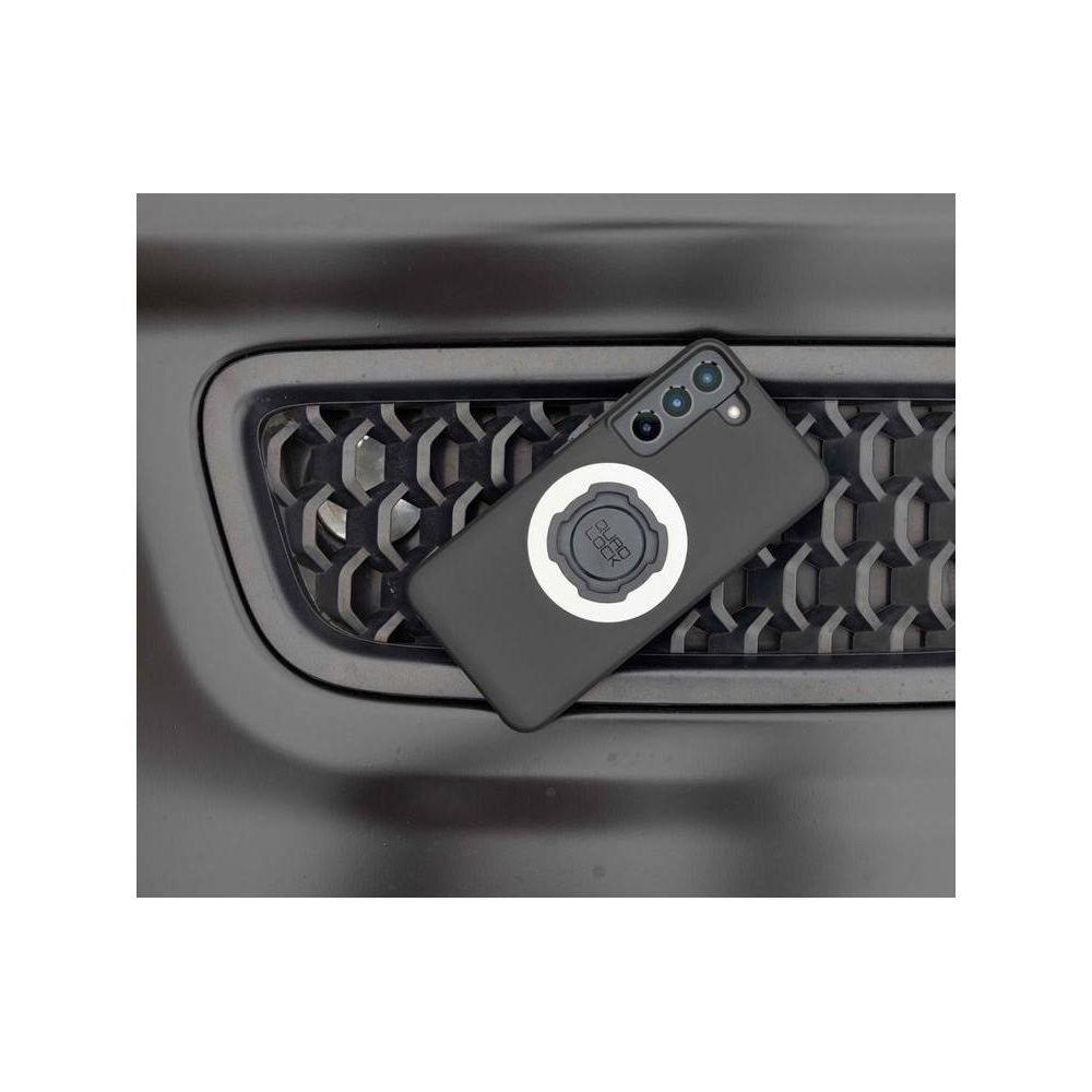 Ein schwarzes Smartphone mit einer runden Halterung liegt auf einem schwarzen Kühlergrill.