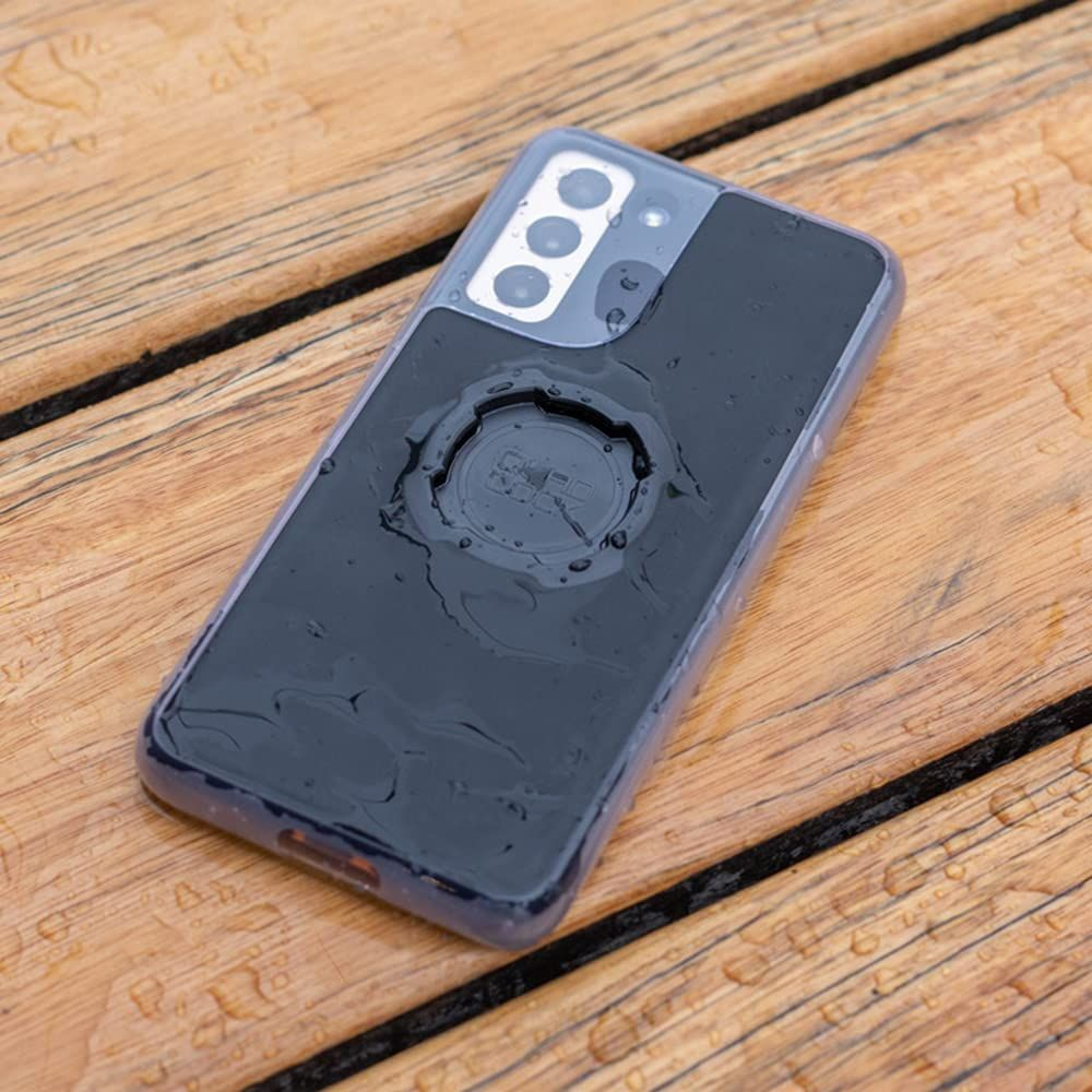 Dunkles Handy mit Quad Lock Halterung auf nassem Holztisch.