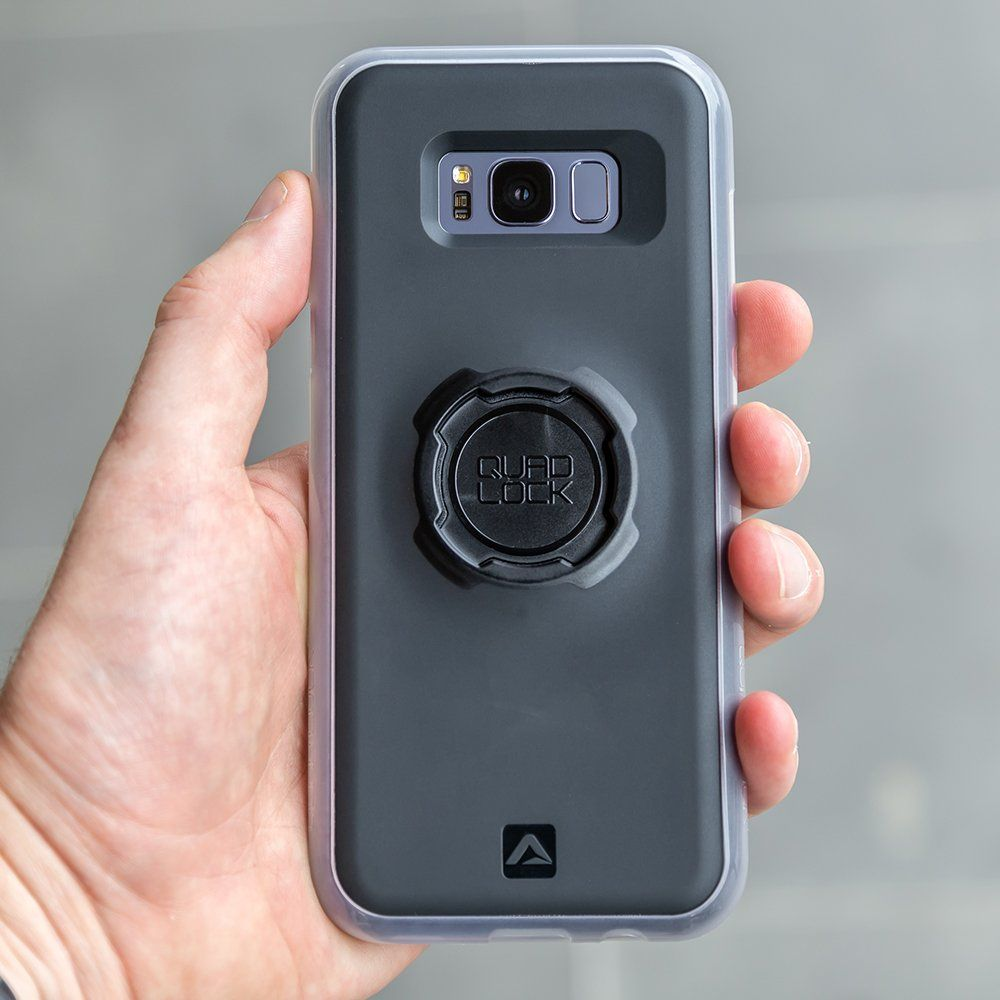 Eine Hand hält ein Smartphone mit einer Quad Lock Hülle und einem schwarzen Ring.