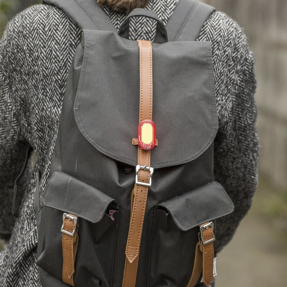 Grauer Rucksack mit braunen Lederriemen und rotem Licht.