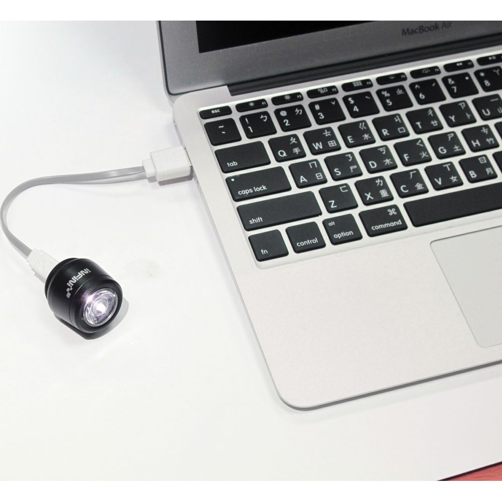 Ein kleiner schwarzer USB-LED-Strahler ist an ein MacBook Air angeschlossen.