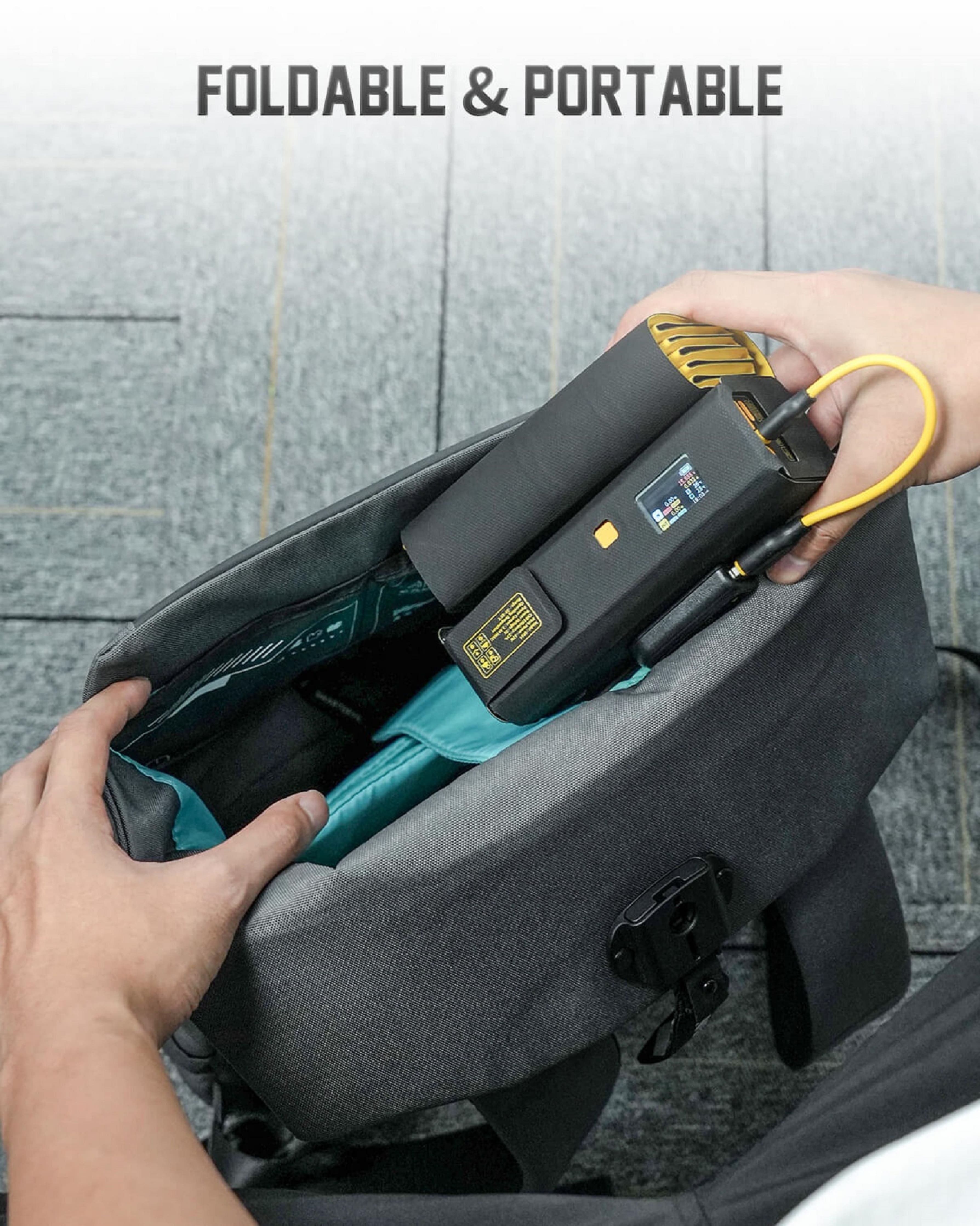Eine Hand legt ein schwarzes und gelbes Gerät in eine graue Tasche.