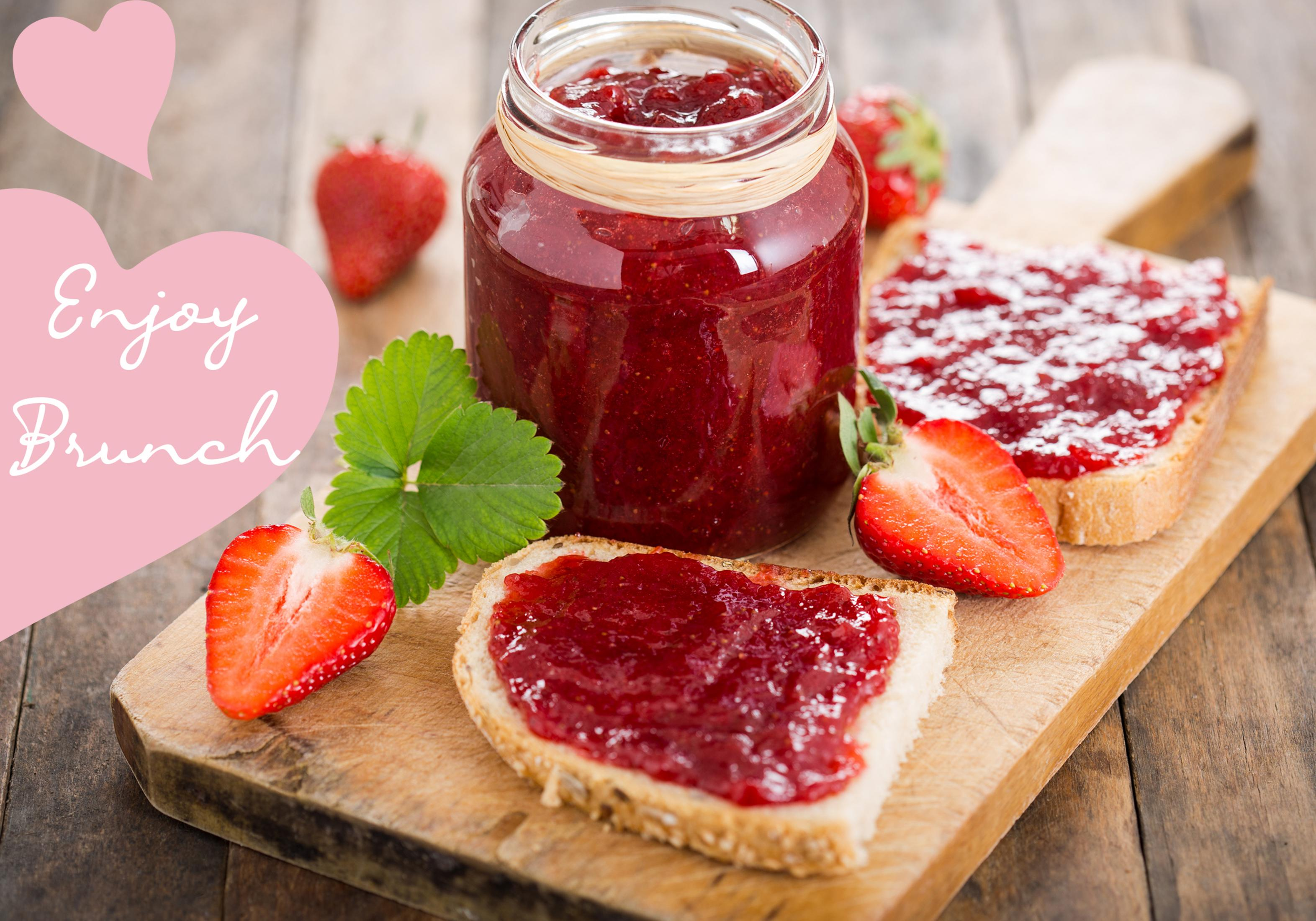 Erdbeermarmelade in einem Glas mit Brot und frischen Erdbeeren auf einem Holzbrett.