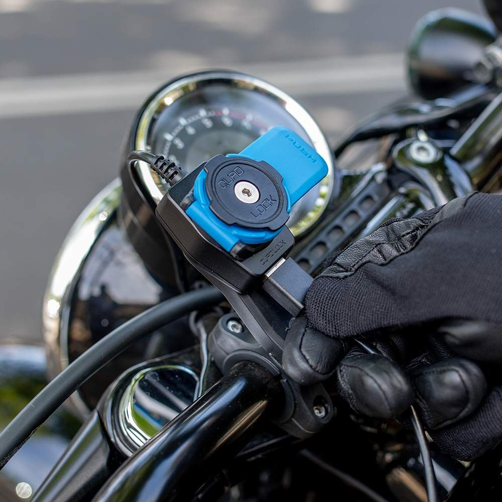 Ein blauer Quad Lock Halter an einem Motorradlenker mit einer Hand in einem schwarzen Handschuh.