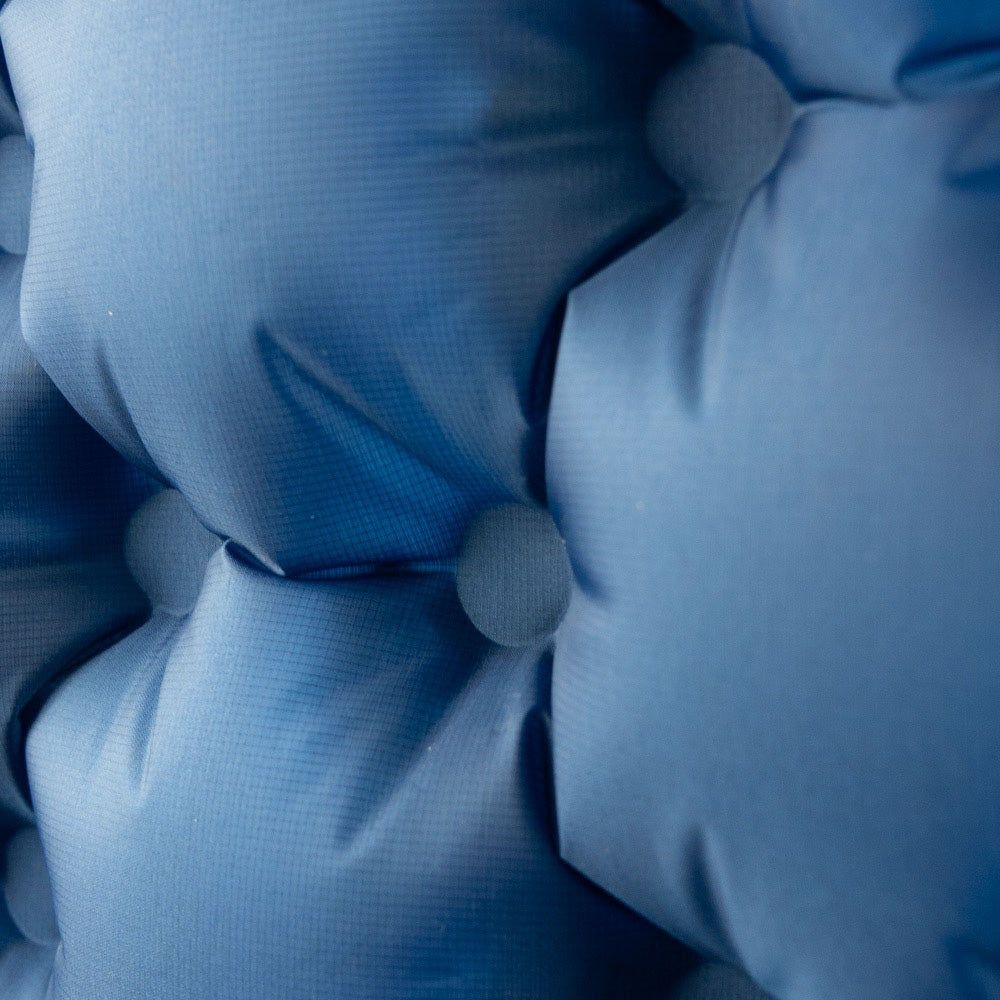 Nahaufnahme einer blauen aufblasbaren Matte mit sichtbaren Nähten und Knöpfen.