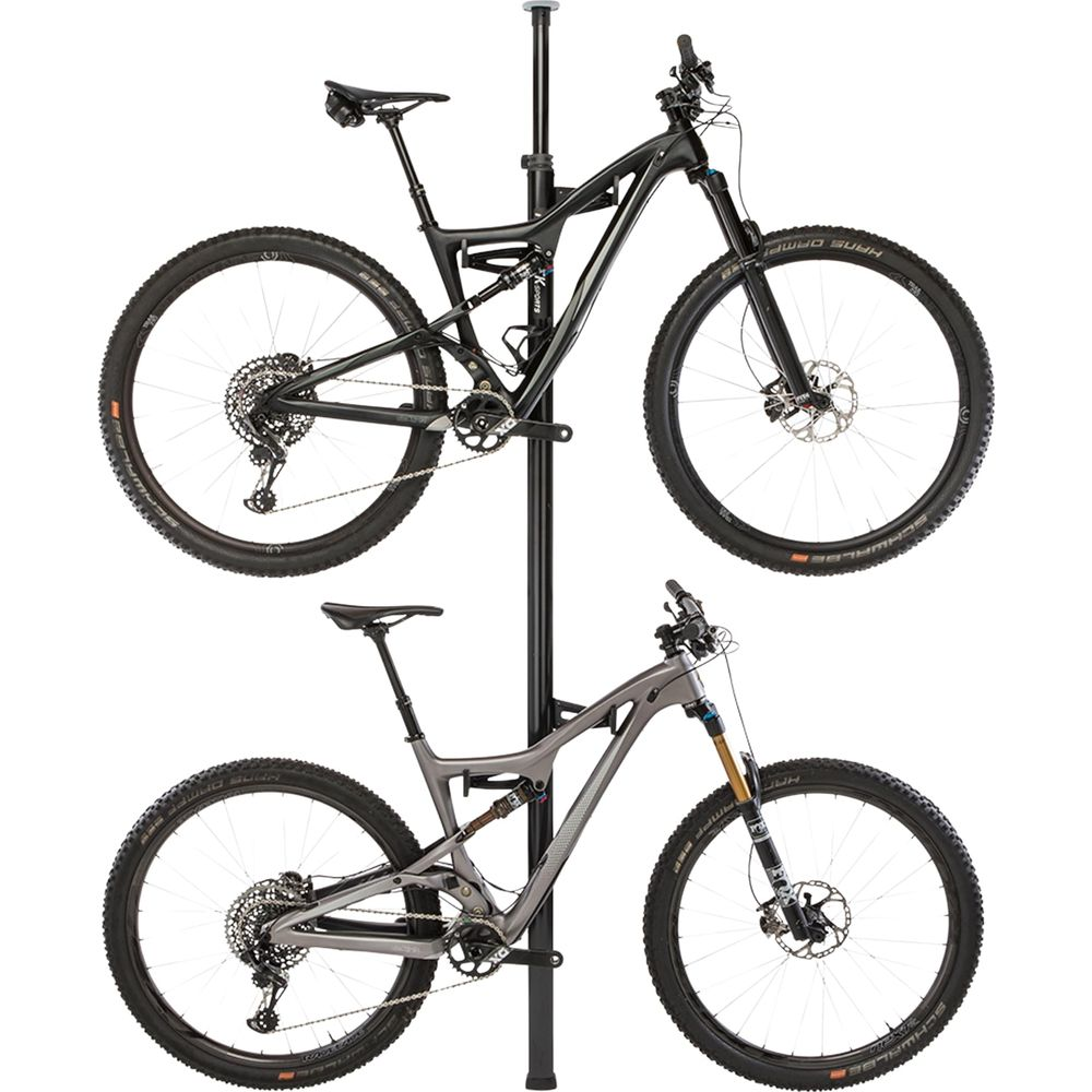 Zwei Mountainbikes, schwarz und grau, hängen an einem Ständer.