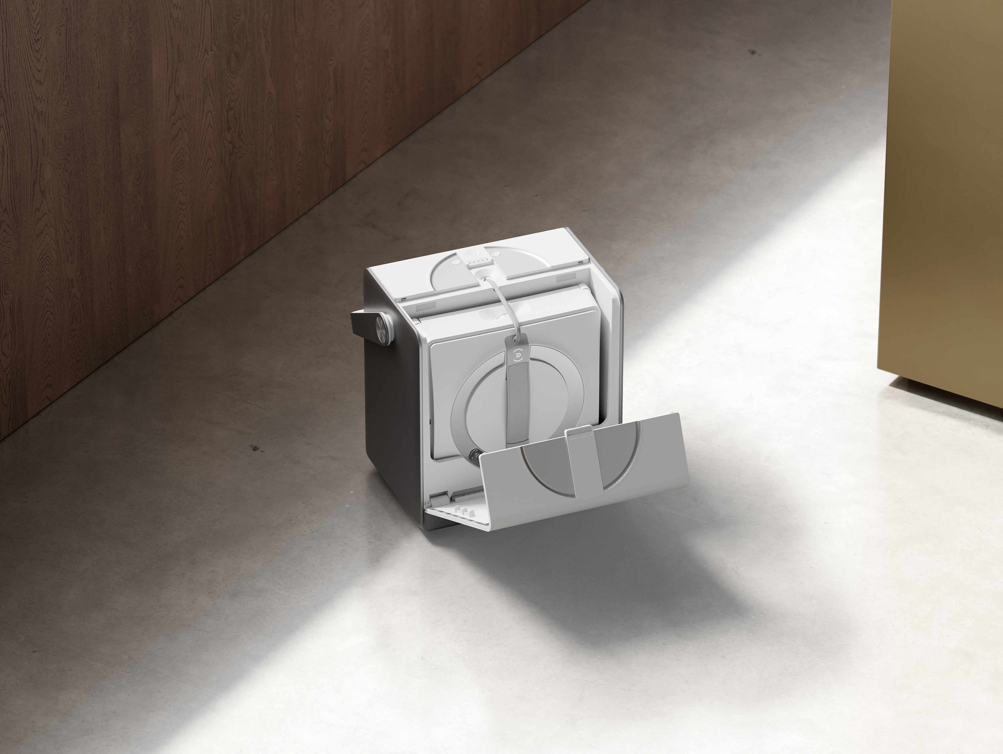 Białe urządzenie z otwartą komorą stoi na betonowej podłodze obok drewnianej boazerii.