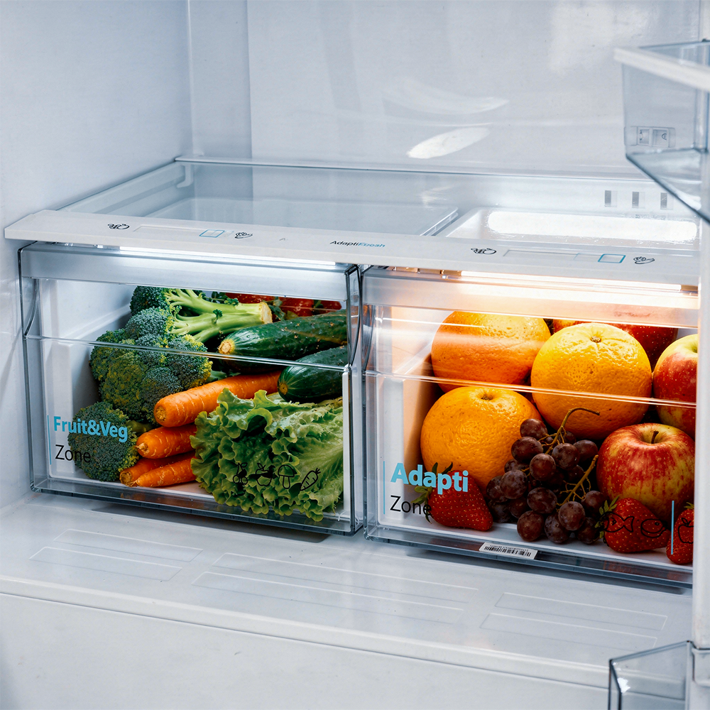 Refrigerator drawers with fruits and vegetables: broccoli, carrots, lettuce, oranges, apples, grapes.