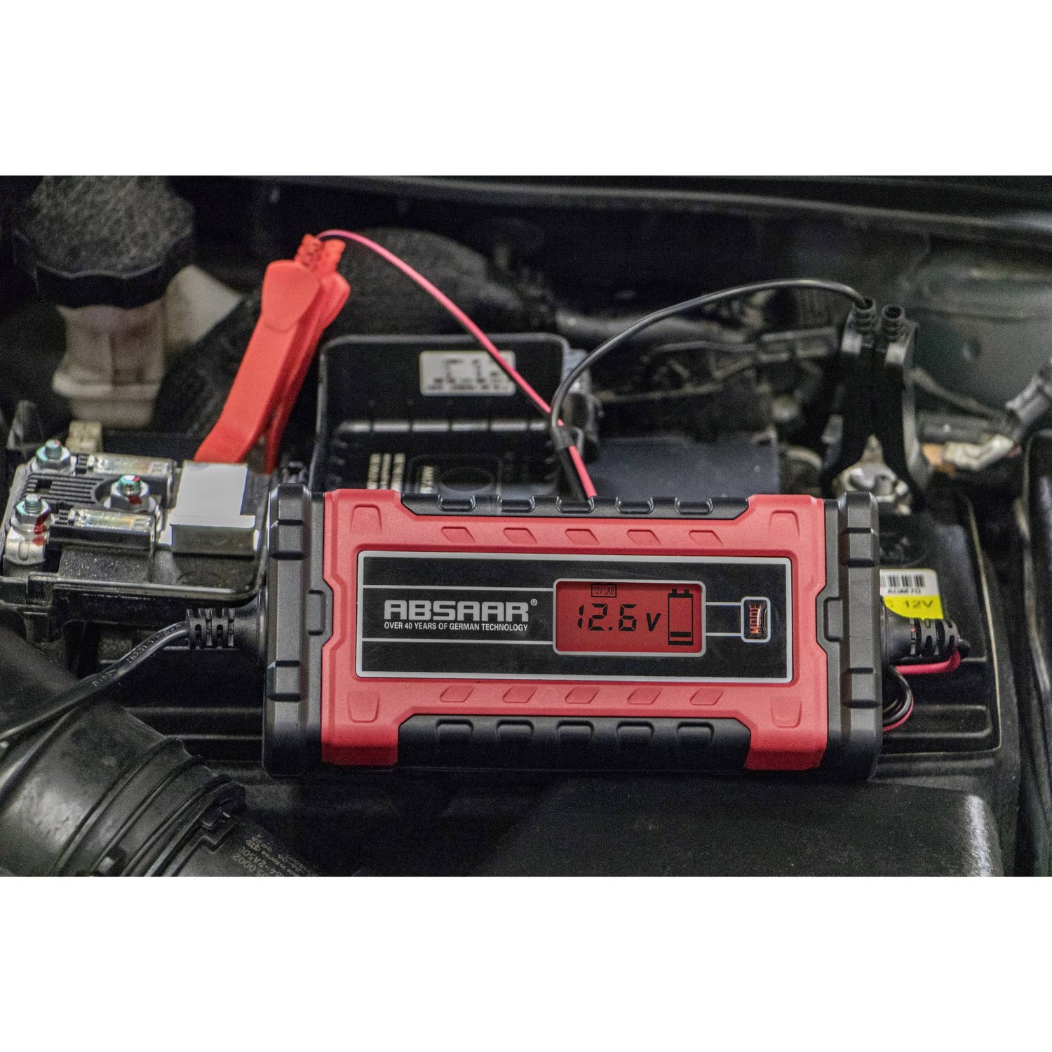 Ein rotes ABSAAR Ladegerät mit 12,6V Anzeige ist an einer Autobatterie angeschlossen.