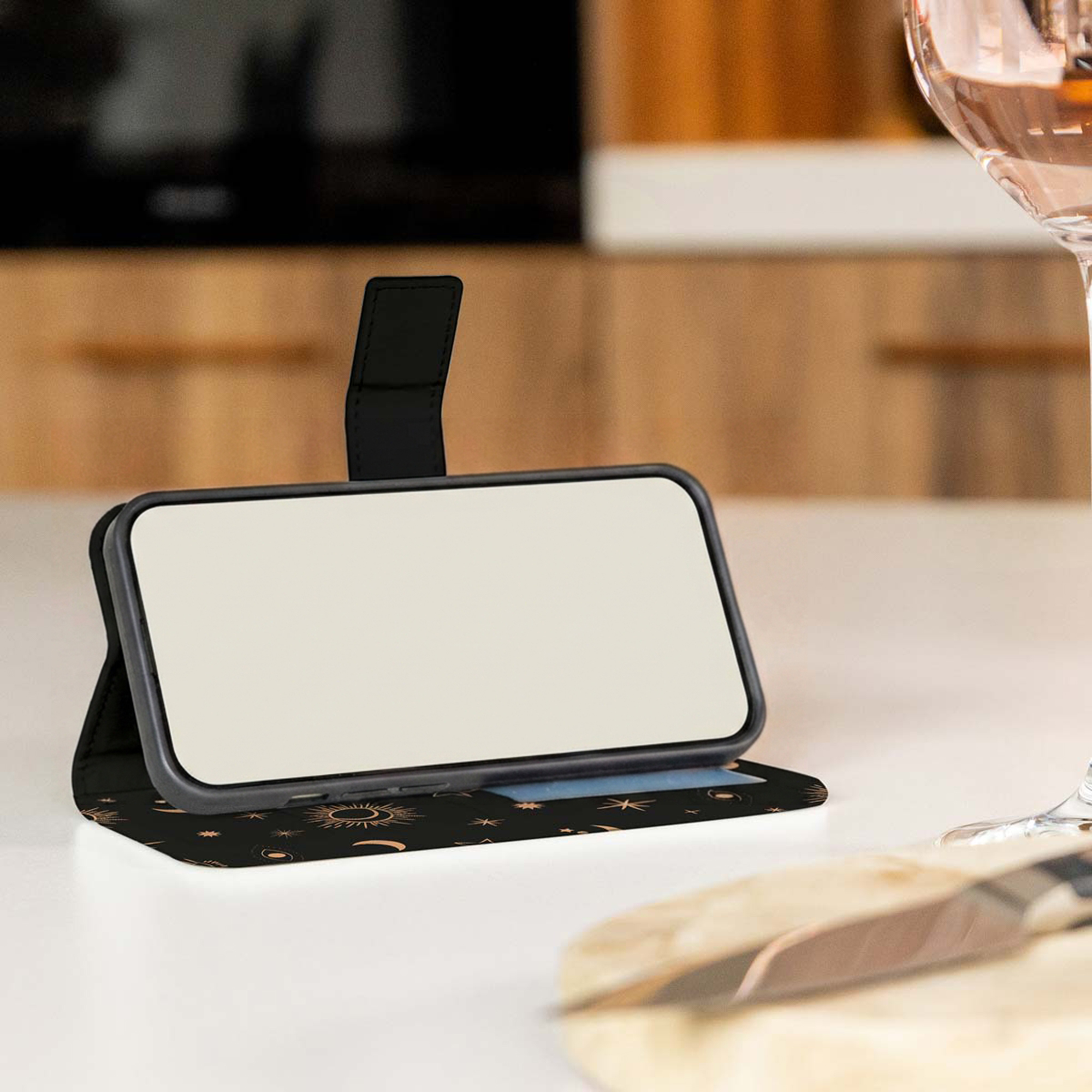 Een telefoon in een zwart hoesje met zonsymbolen rust op een tafel.