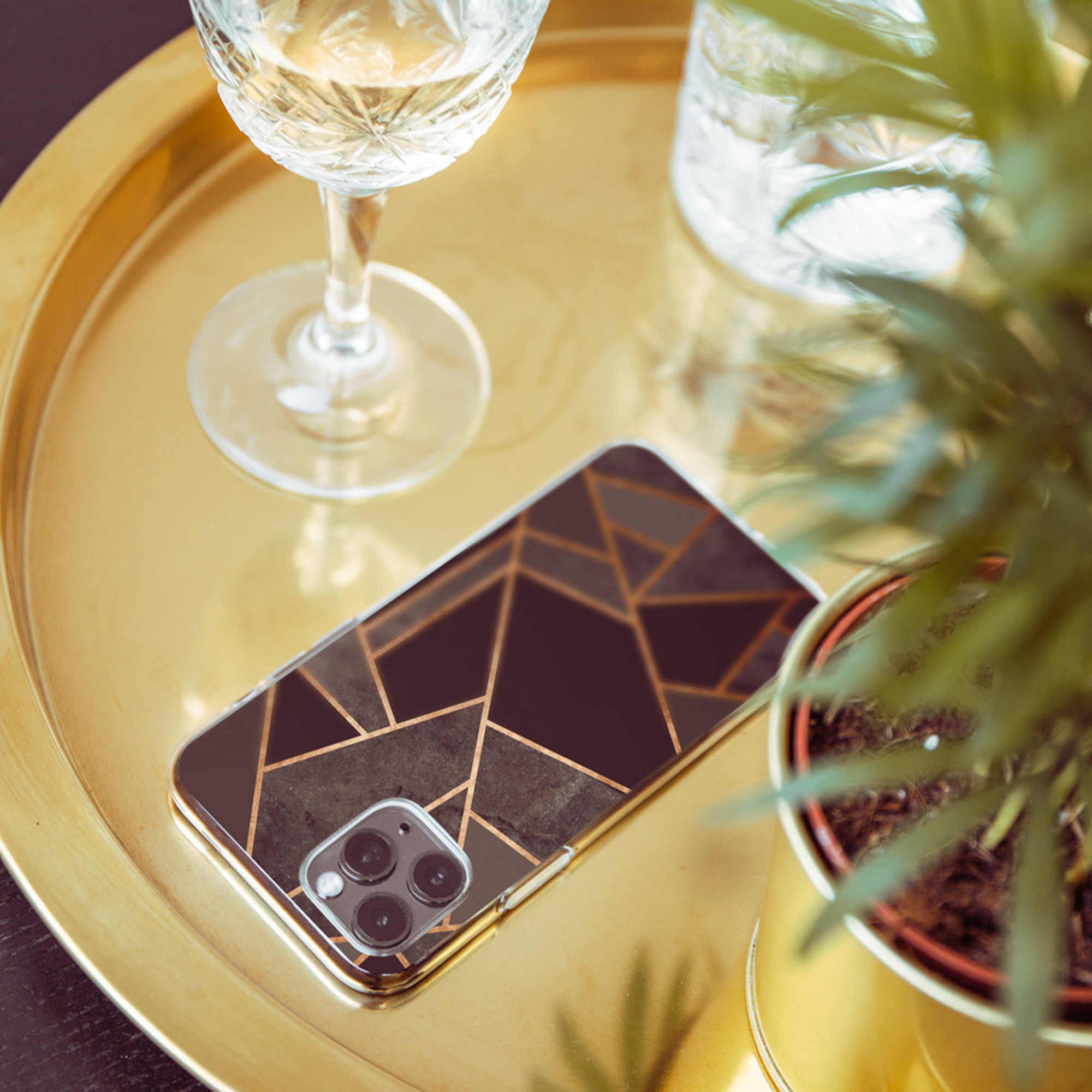 Vasso dorato con telefono, bicchiere e pianta.