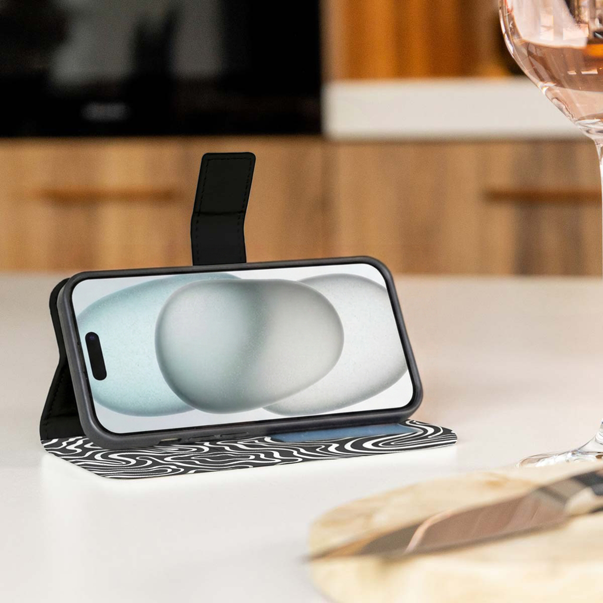 Een telefoon in een zwart patroonhoes staat op een tafel.