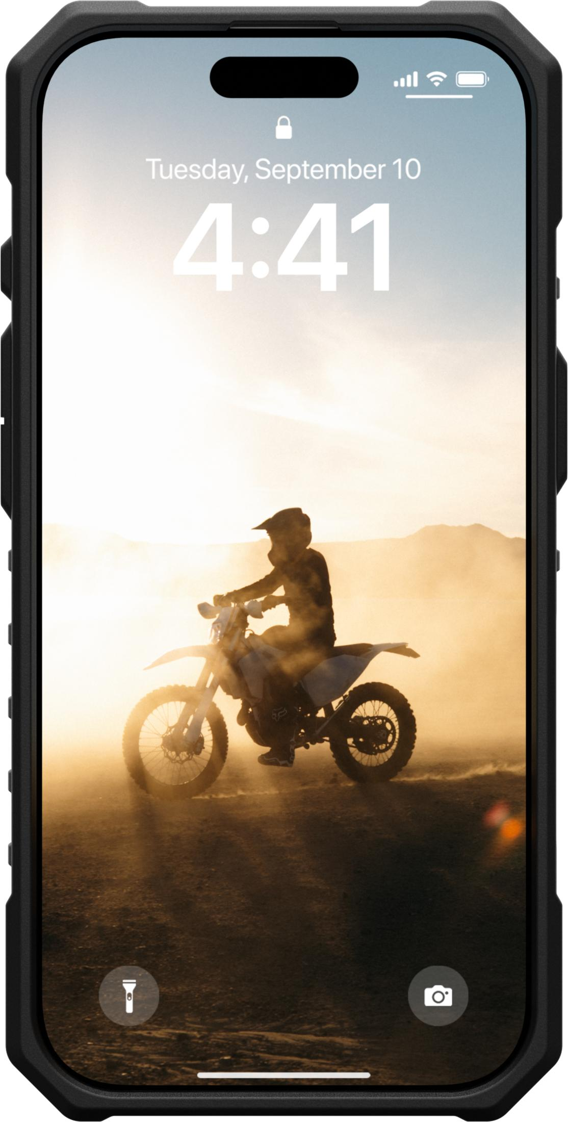 Ein Motorradfahrer fährt im Sonnenuntergang durch Staub.