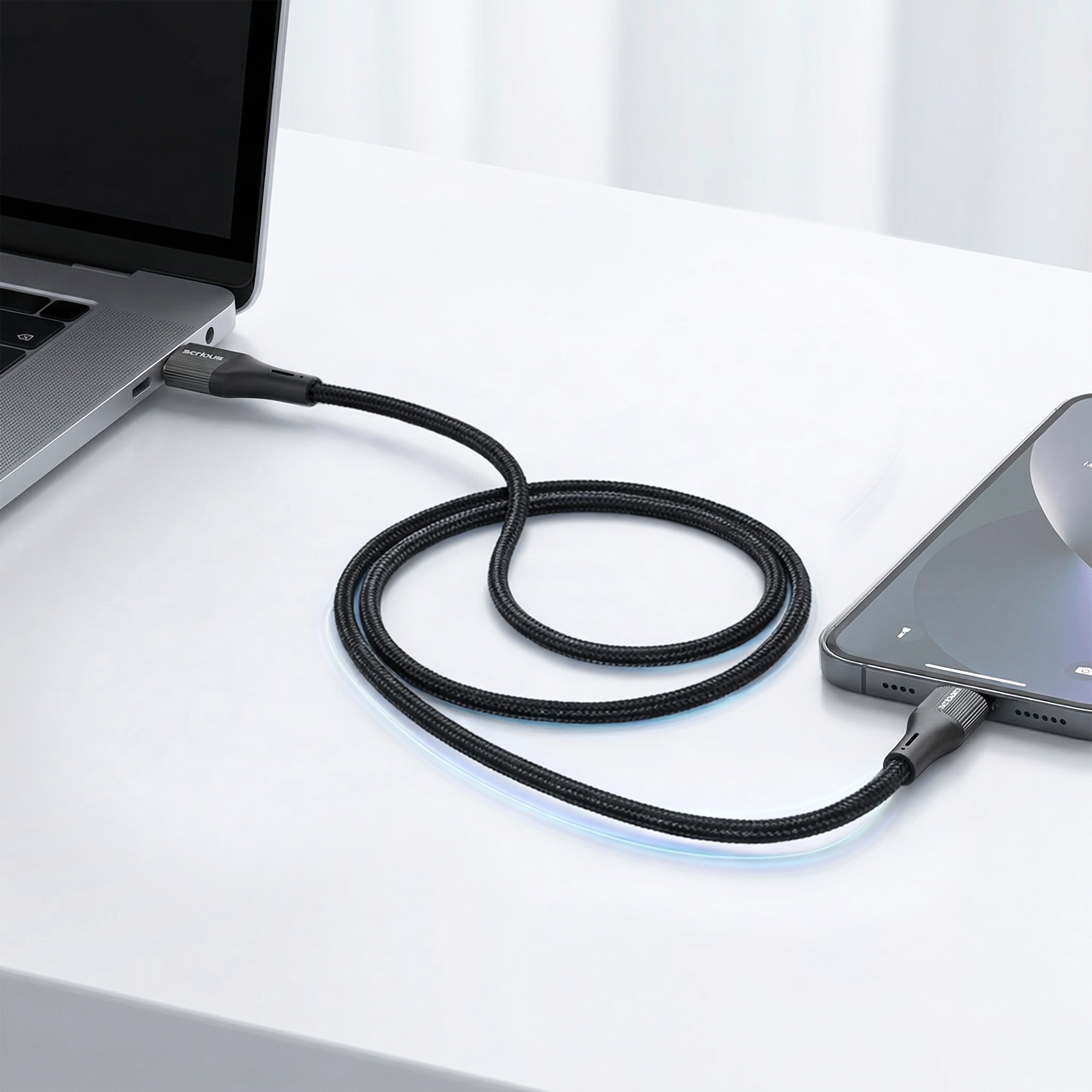 Een zwarte USB-C-kabel verbindt een laptop met een smartphone op een witte tafel.