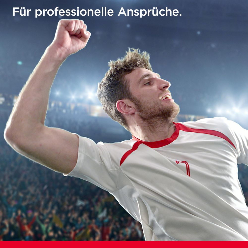 Fußballspieler jubelt mit erhobener Faust in einem Stadion voller Fans.