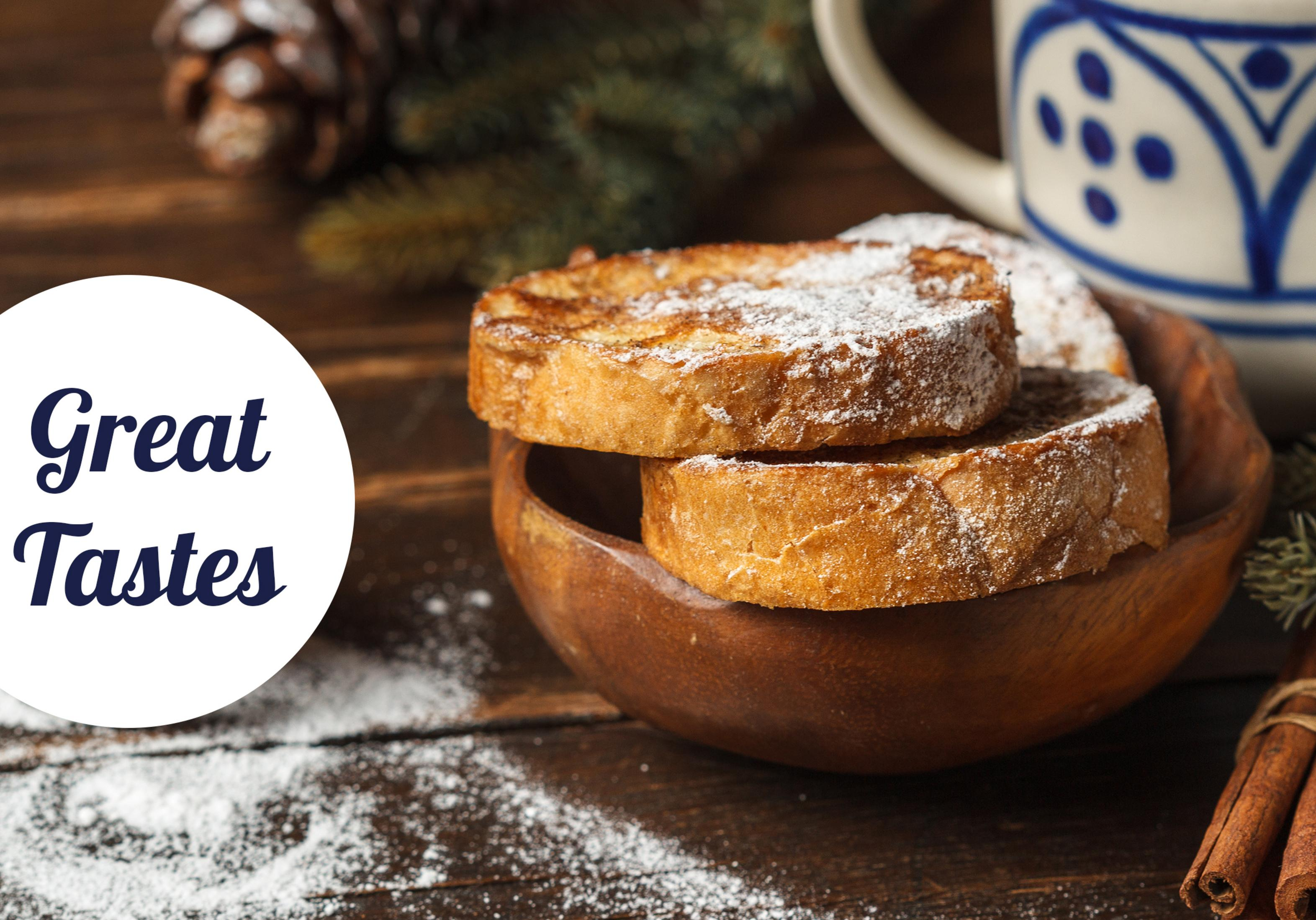 Zimt-French-Toast mit Puderzucker in einer Holzschale, daneben eine Tasse und Zimtstangen.