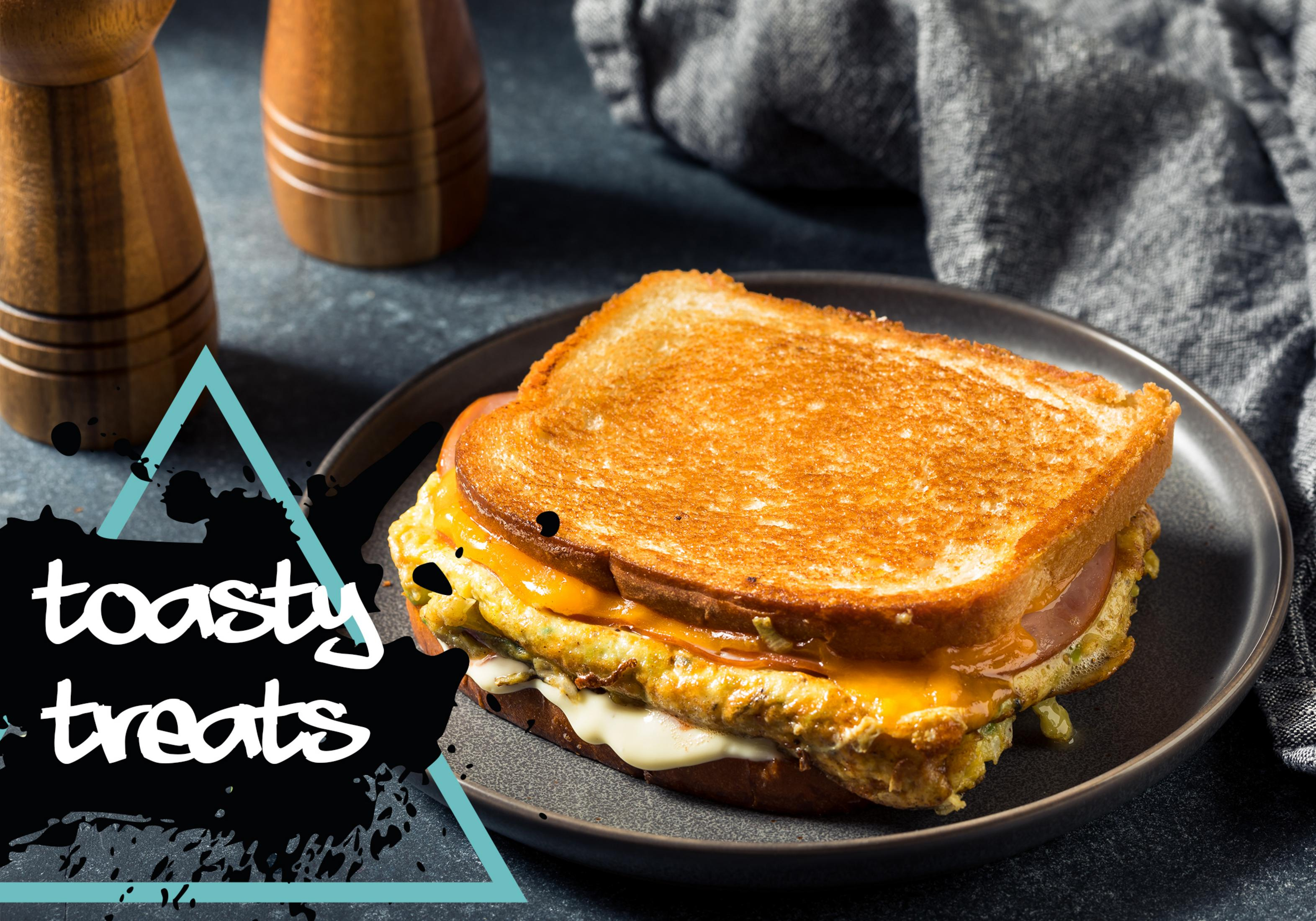 Un sandwich grillé au fromage et jambon sur une assiette sombre.