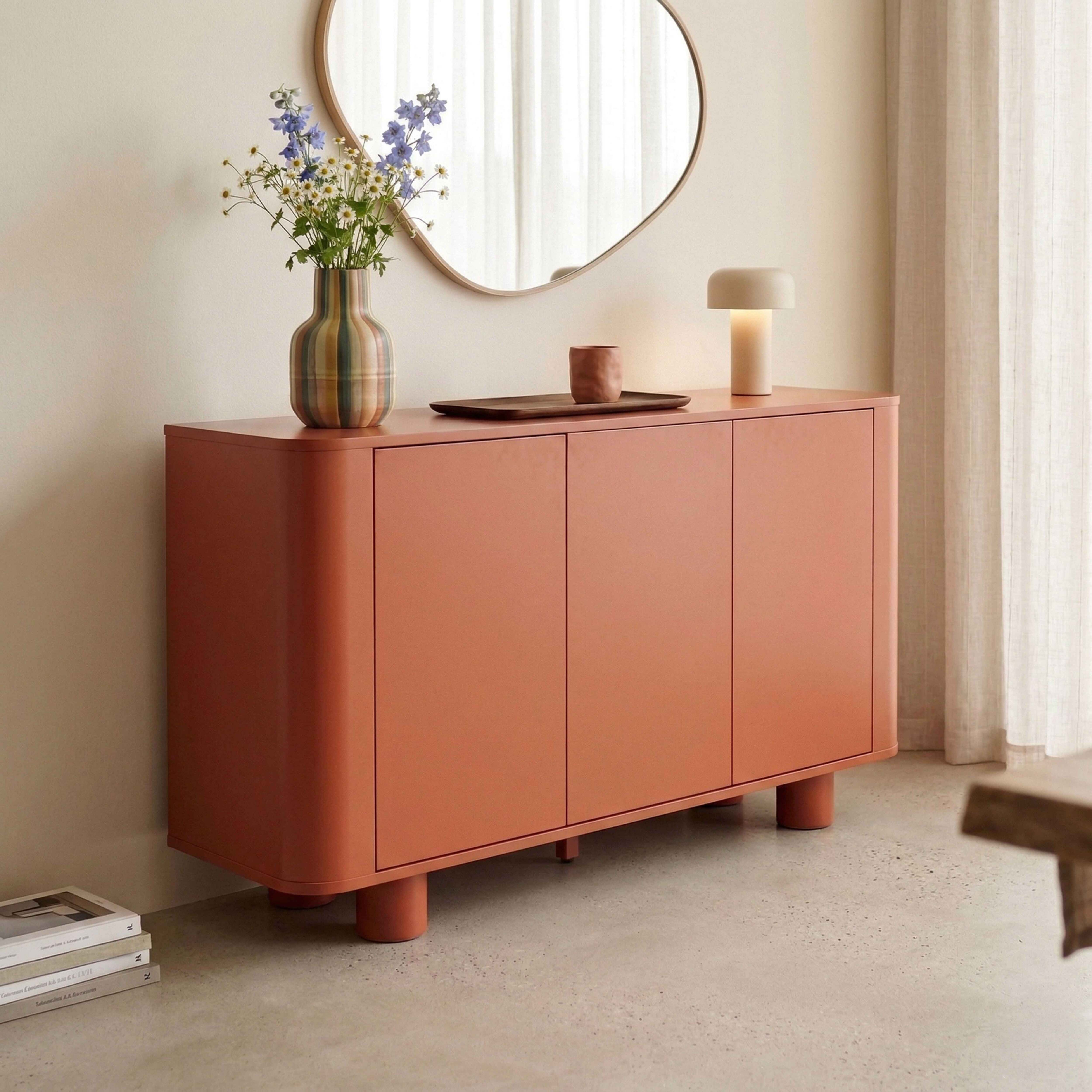 Ein korallenrotes Sideboard mit runden Beinen steht auf einem Terrazzoboden.