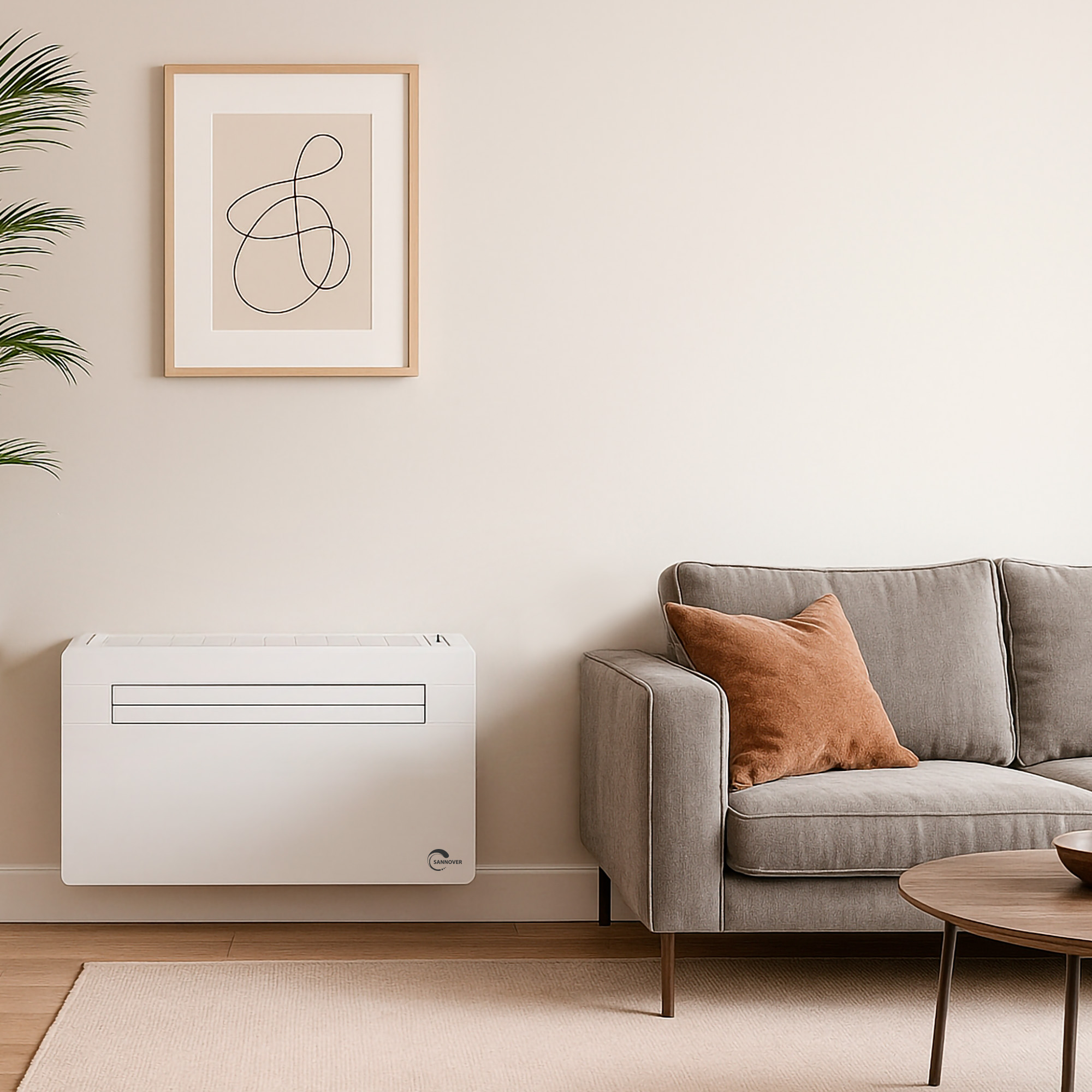 Een witte airconditioning unit staat onder een ingelijste foto aan een muur, naast een grijze bank.
