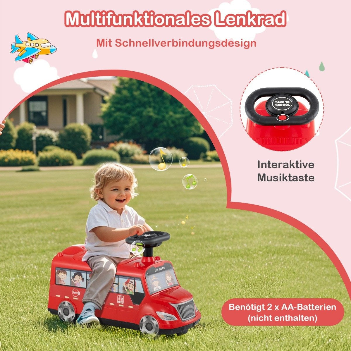 A toddler rides a red toy bus on a green lawn. A steering wheel is visible.