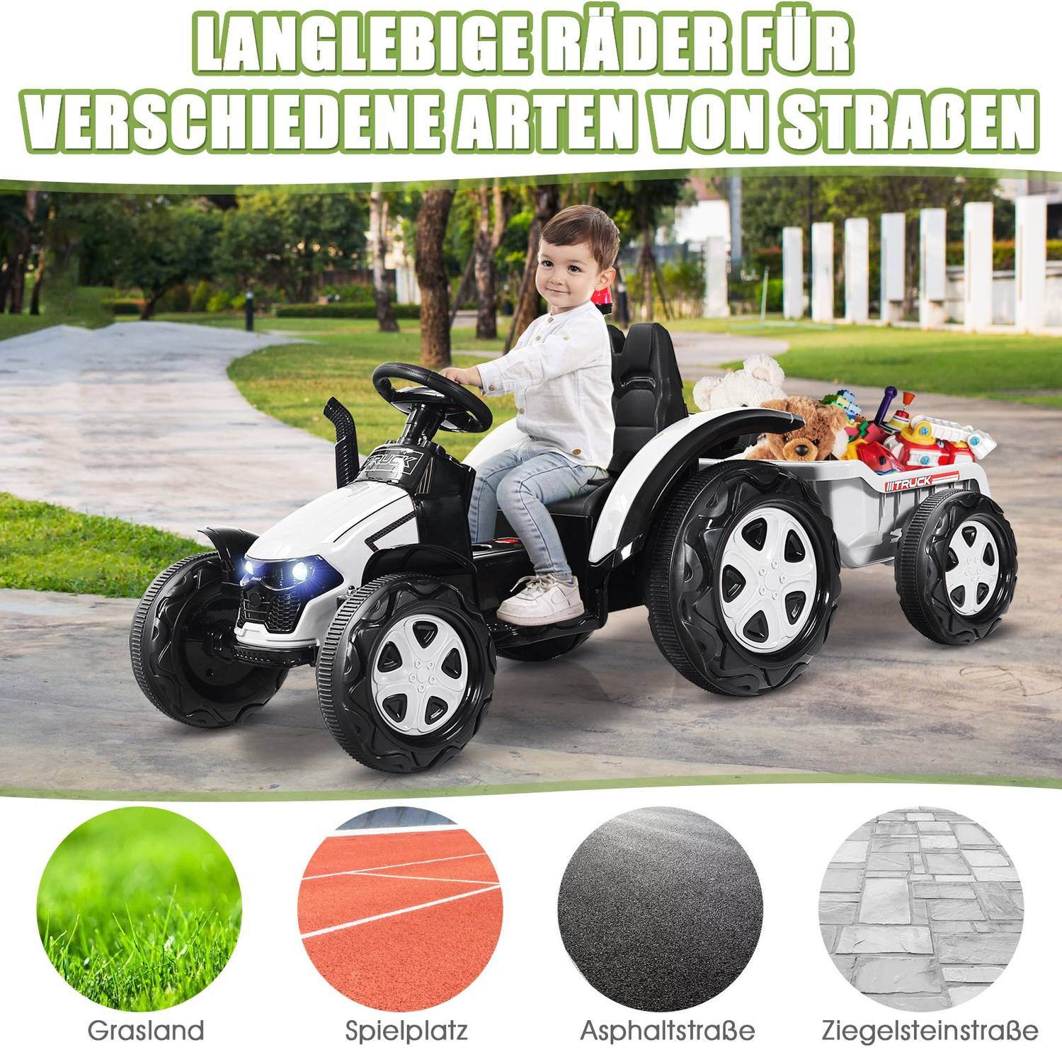 A boy rides a white toy tractor with a trailer full of toys outdoors.
