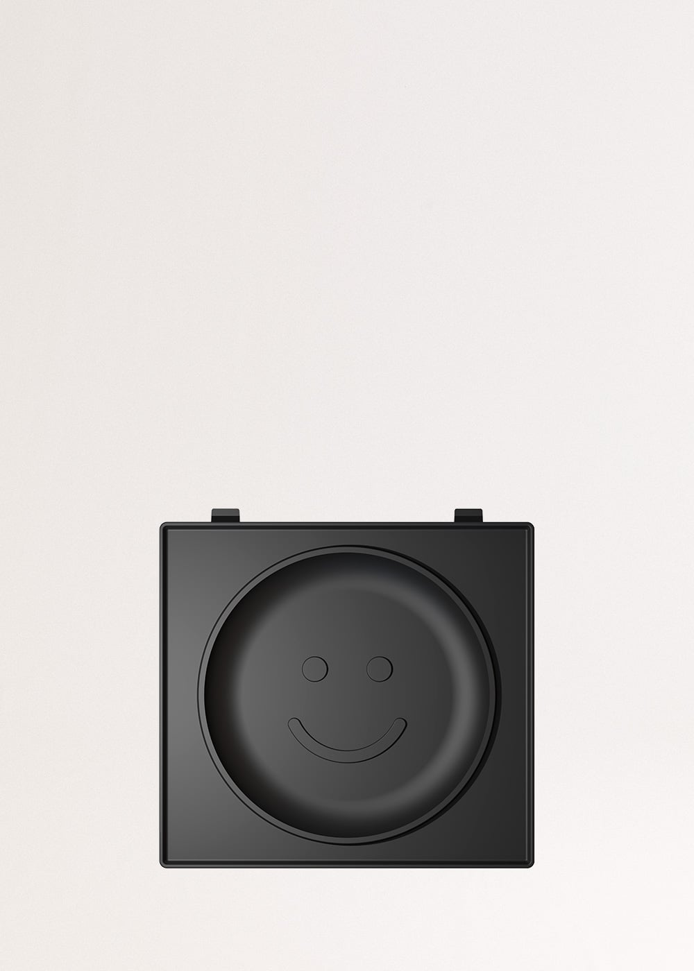 Un contenedor negro con diseño de cara sonriente, sobre un fondo claro.