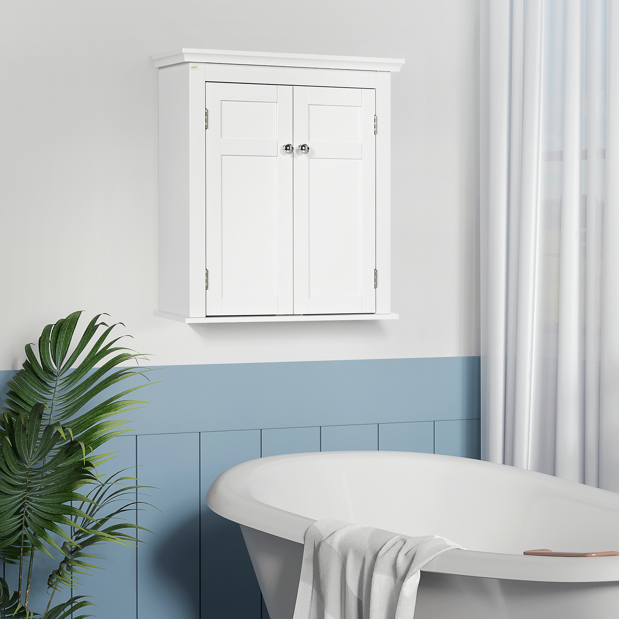 Un armario blanco de pared con doble puerta cuelga sobre una bañera. Una planta a la izquierda.