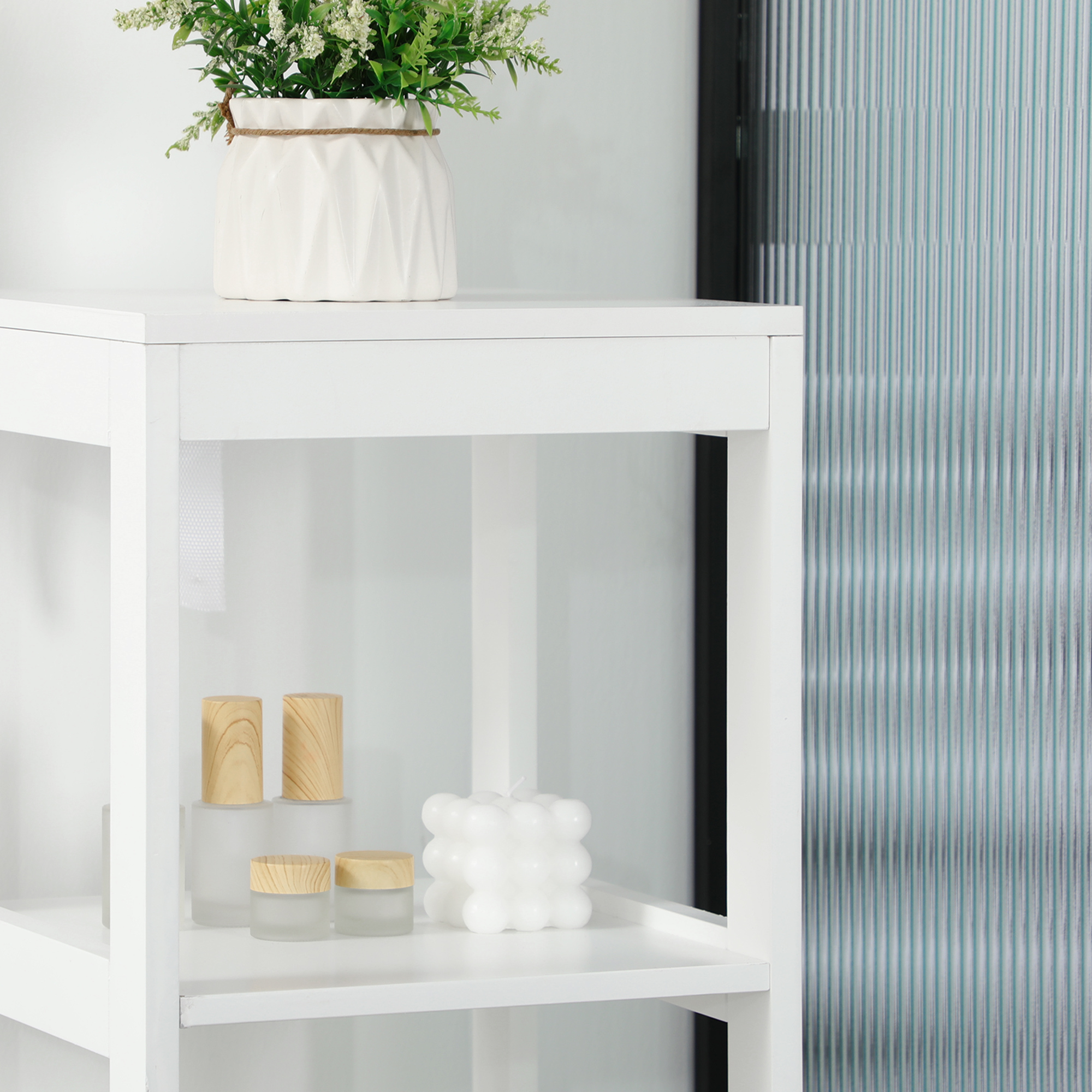 Un estante blanco con plantas, velas y tarros.