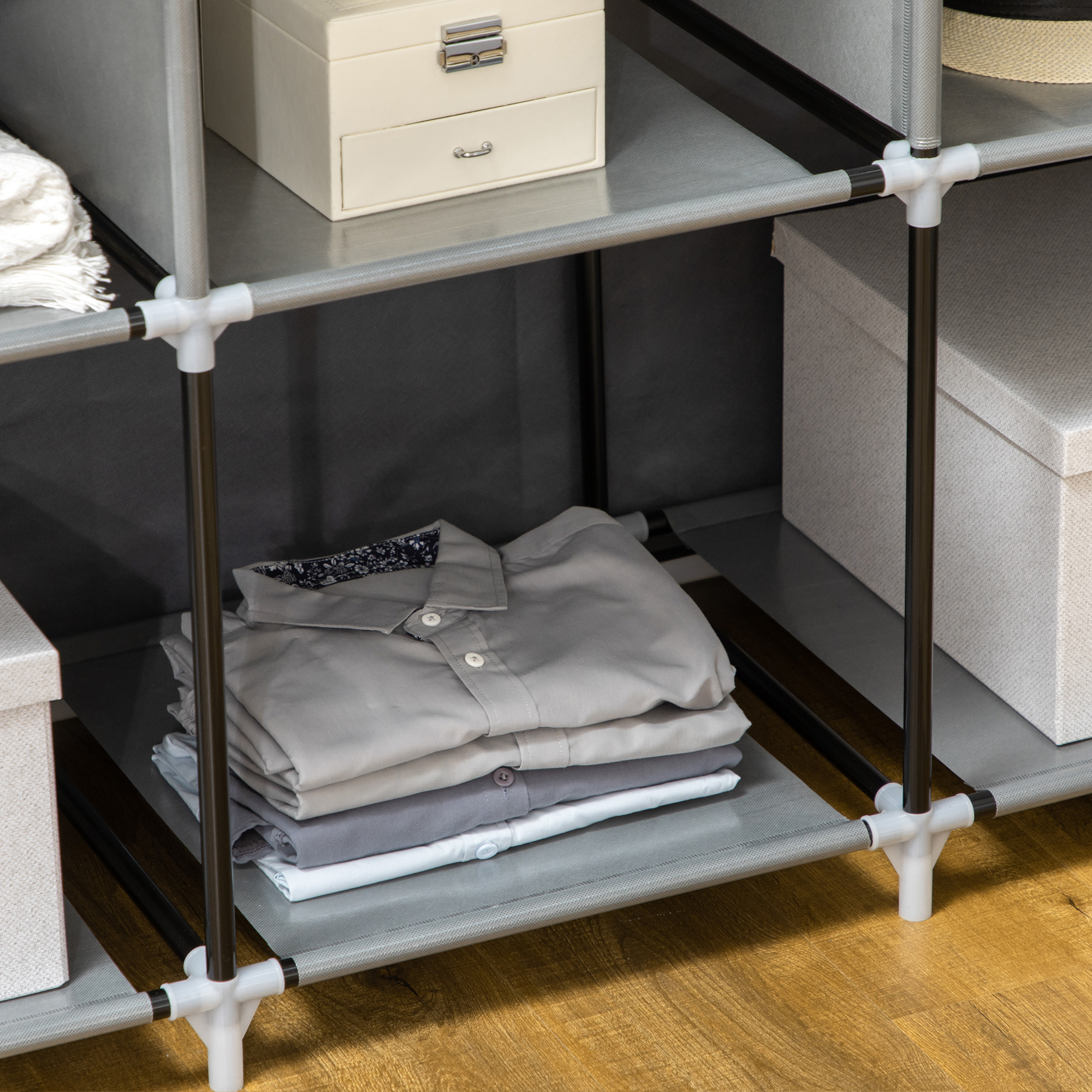 Camisas apiladas en tonos grises y blancos en un estante de un armario de tela.