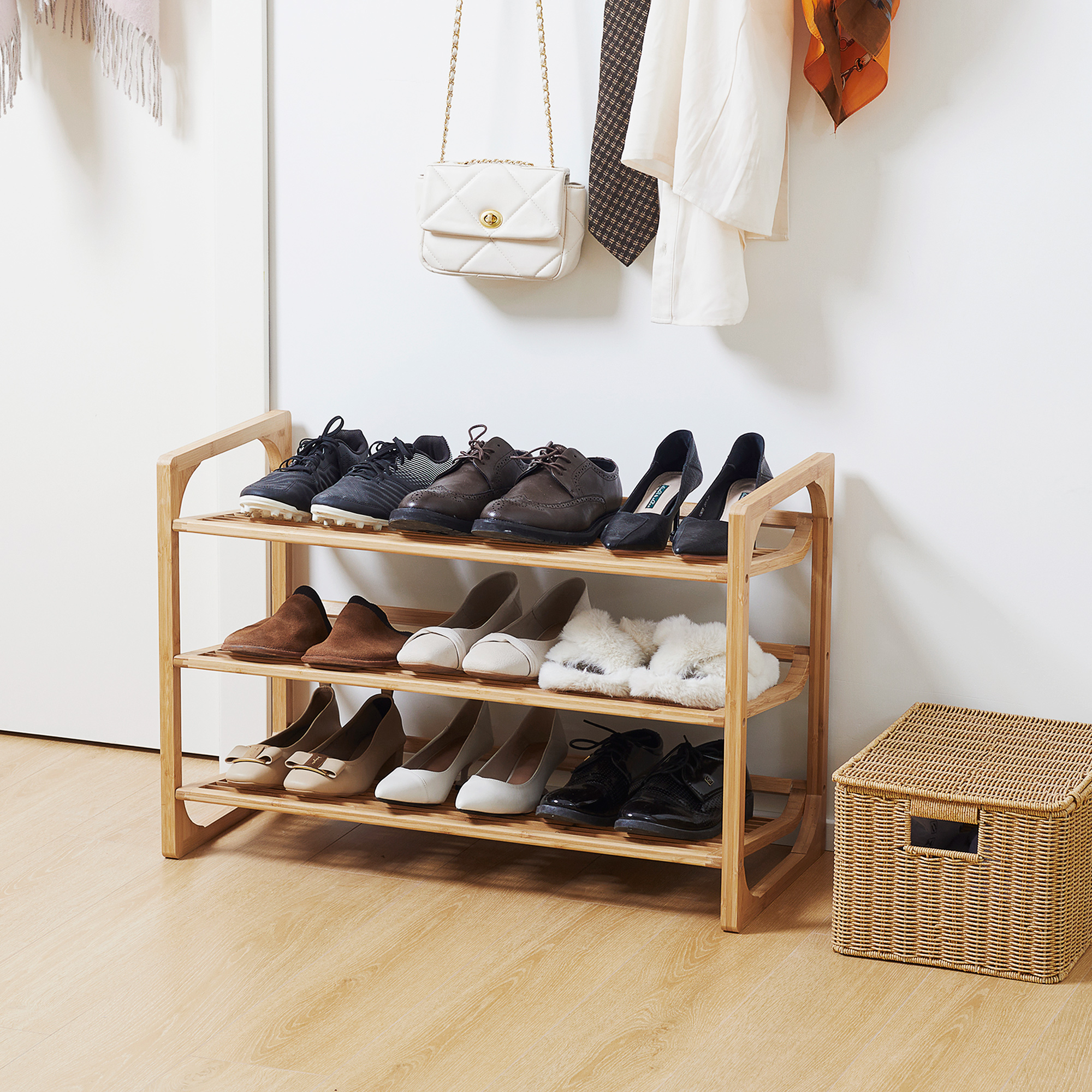 Zapatero de madera con 3 estantes que sostienen varios zapatos, un bolso y ropa.