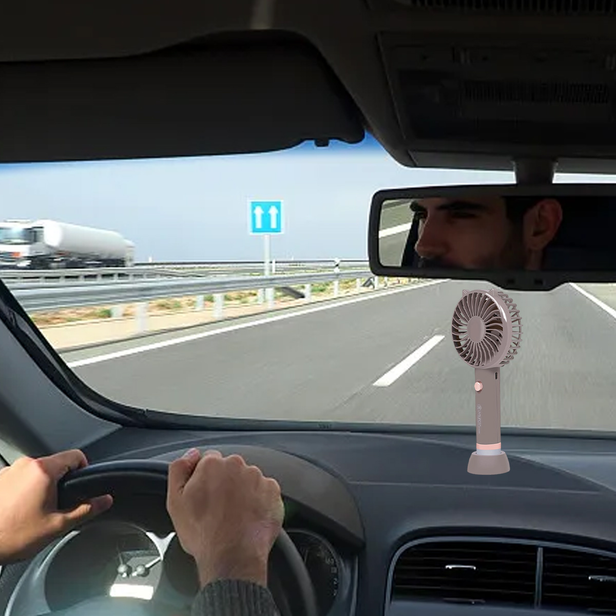 Ein Fahrer hält das Lenkrad, ein kleiner Ventilator steht auf dem Armaturenbrett.