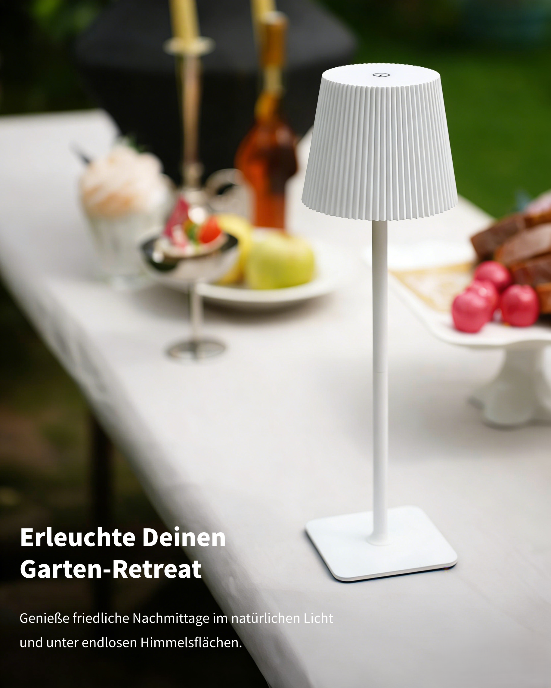 Weiße Tischlampe auf einem Gartentisch mit Essen und Getränken.