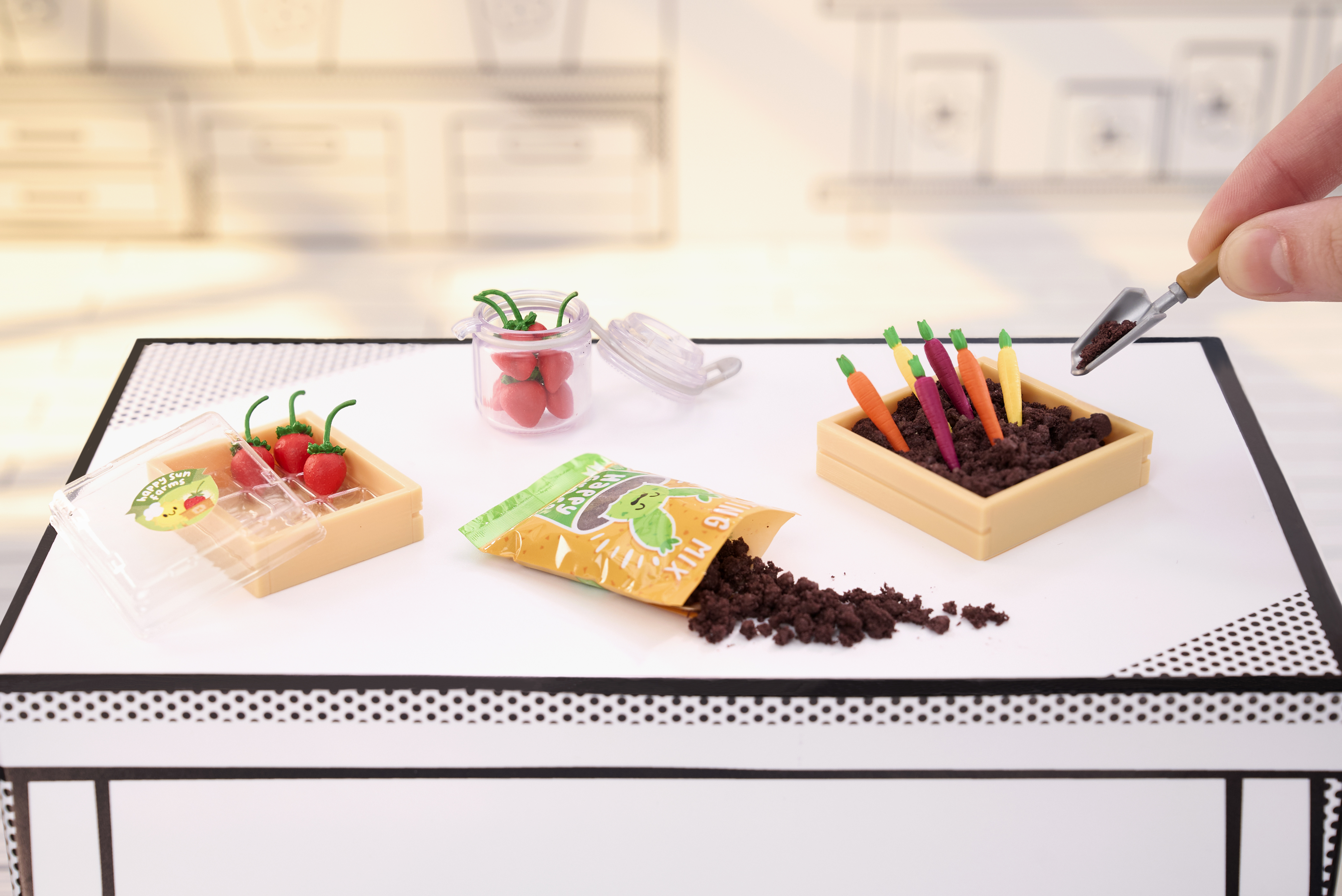 Scena di giardinaggio in miniatura: fragole in contenitore, carote nel terreno, sacchetto terra.