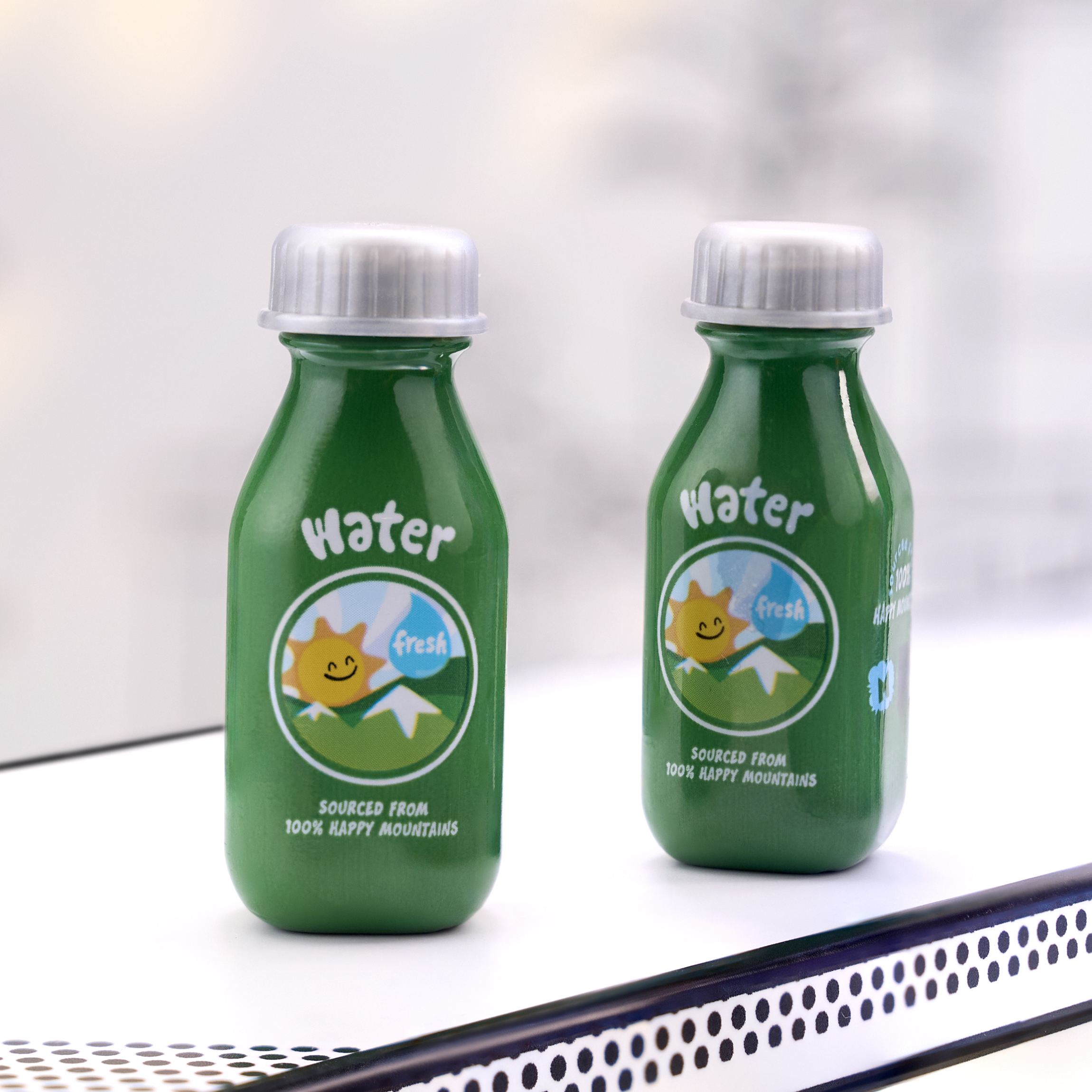 Due bottiglie d'acqua verdi con tappi ed etichette argentate.