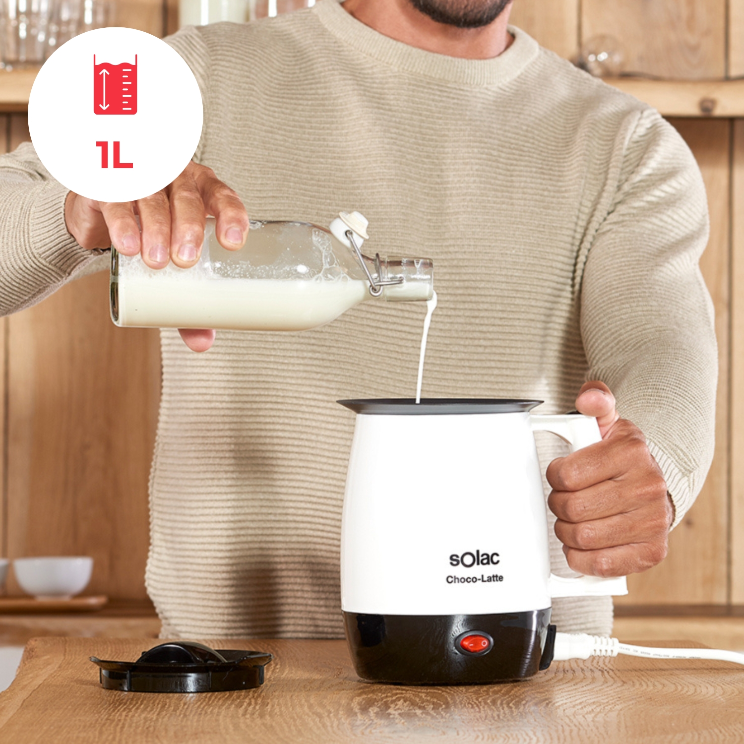 Hombre vierte leche de botella en espumador blanco con marca de 1L.