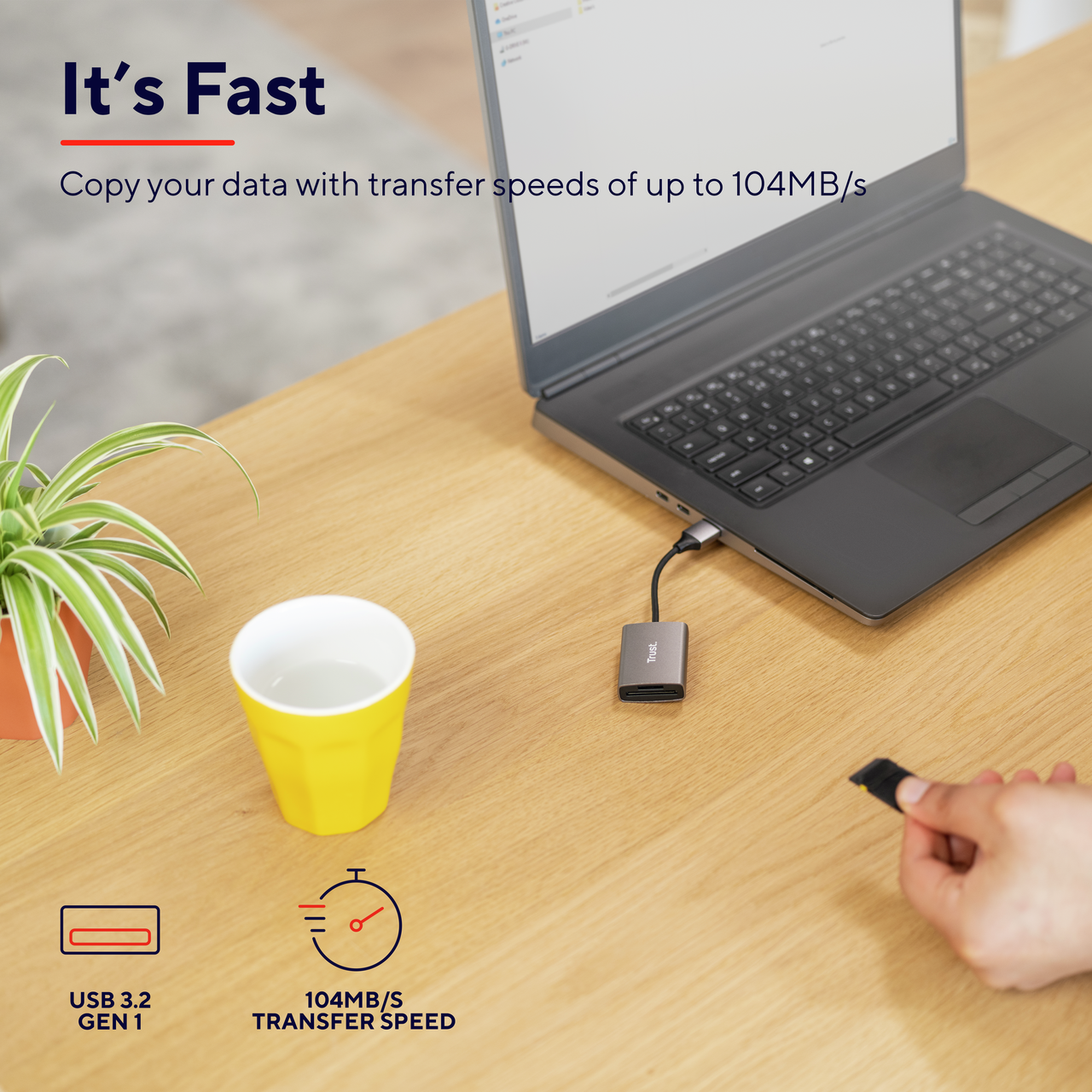 Laptop podłączony do czytnika kart na drewnianym biurku. Tekst brzmi: „Szybko”.