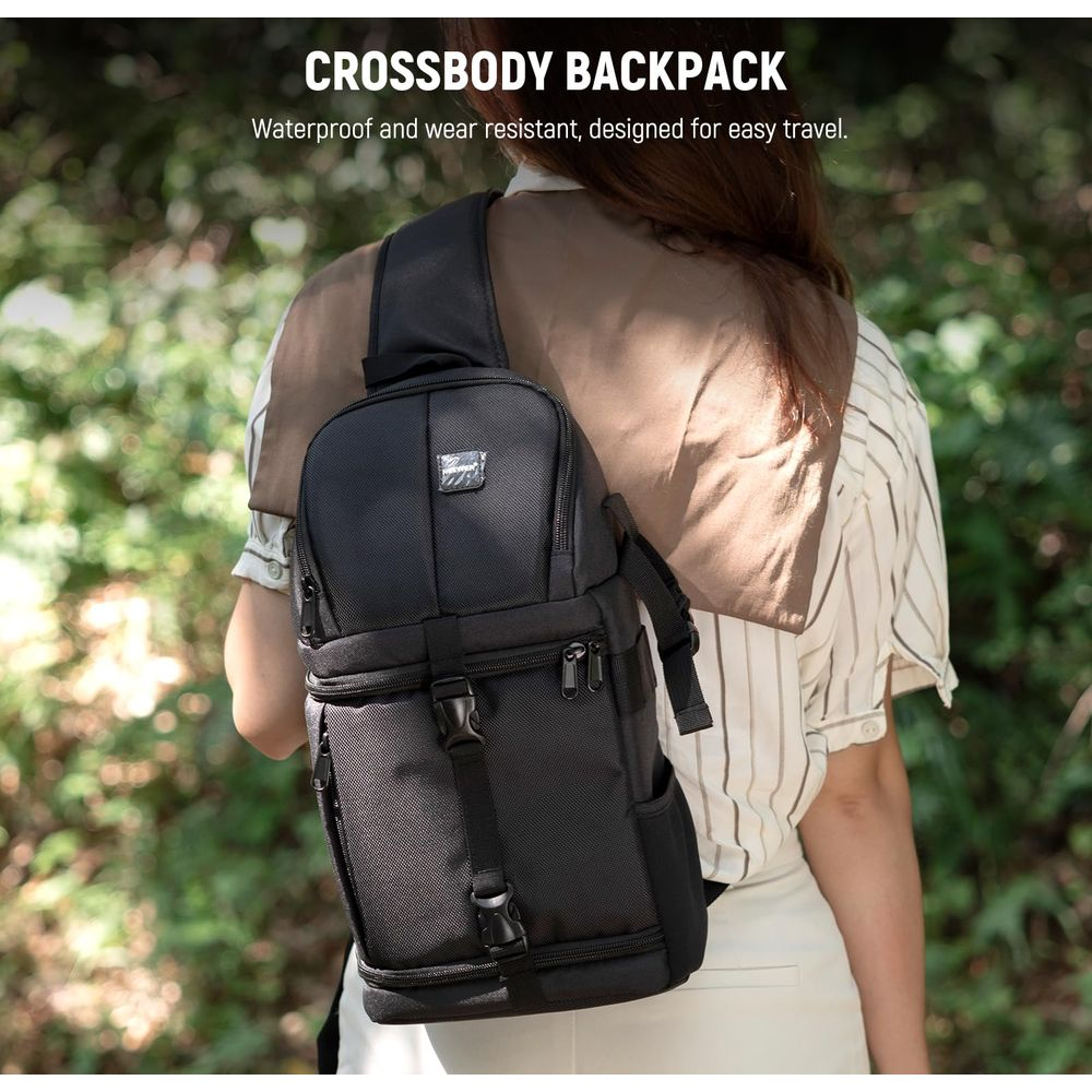 Zwarte crossbody rugzak met gespen en ritsen, gedragen door een persoon buiten.