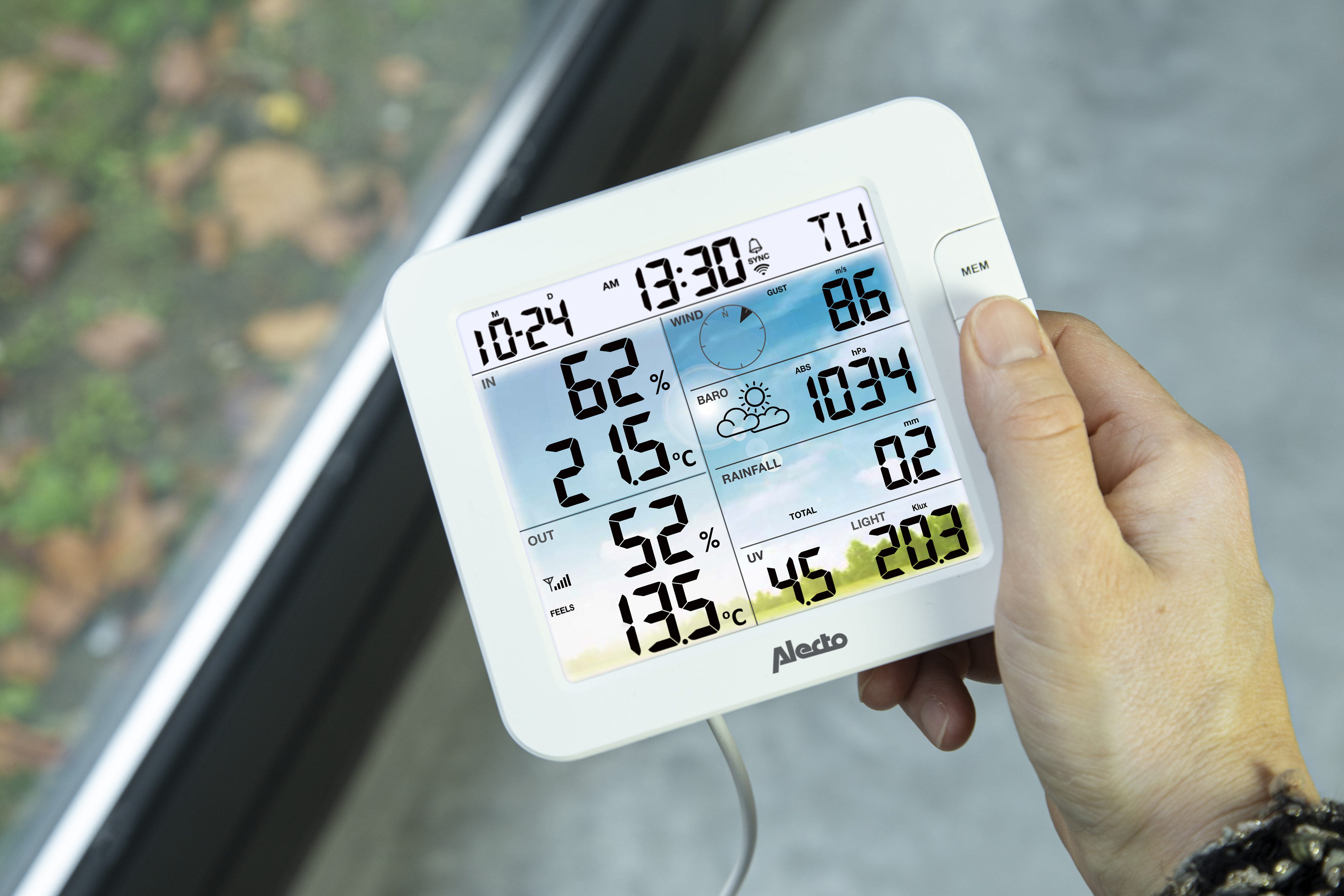 Ein Wetterstation-Display zeigt Innen-/Außentemperatur, Windgeschwindigkeit und Luftdruck.