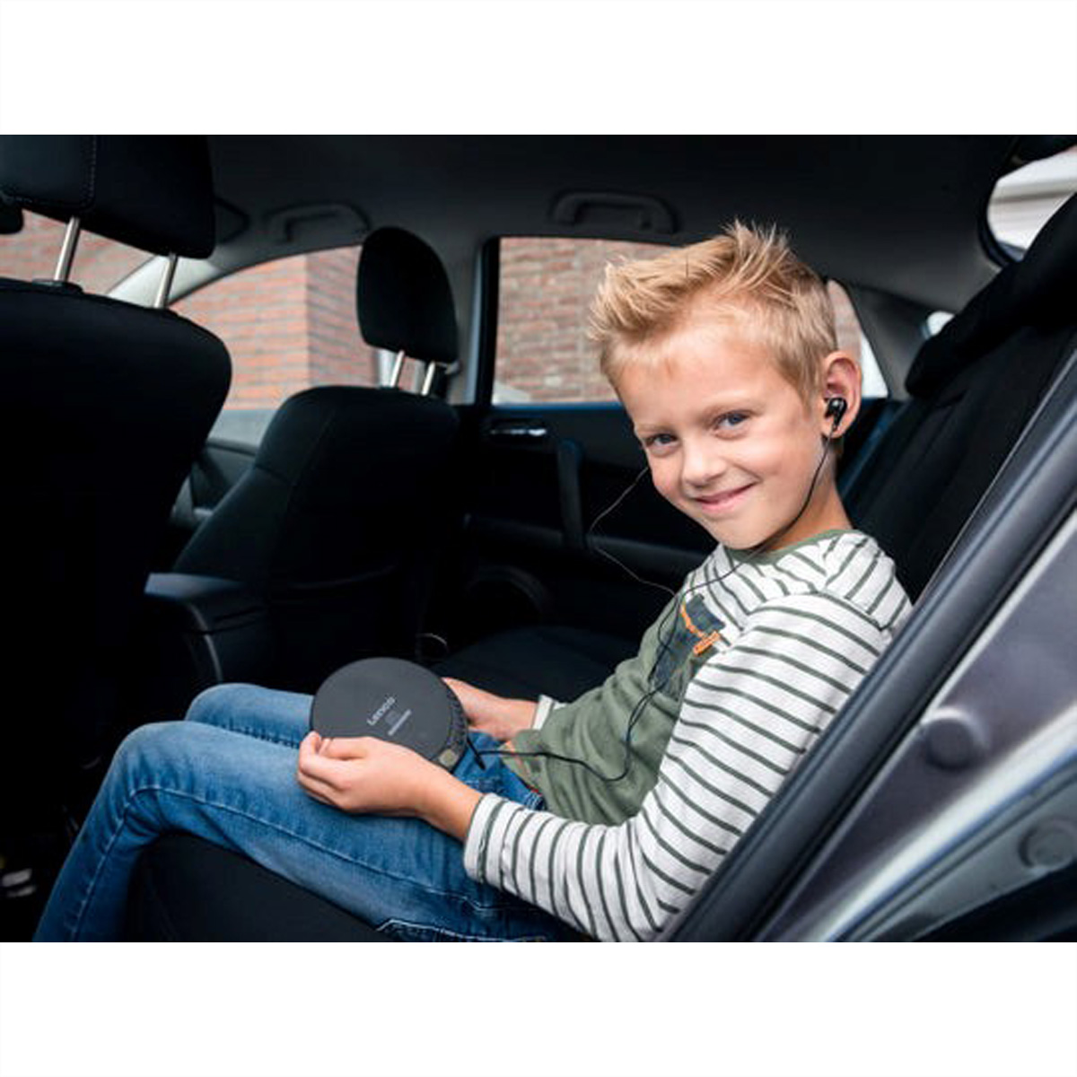 Chłopiec siedzi w samochodzie i słucha muzyki przez słuchawki.