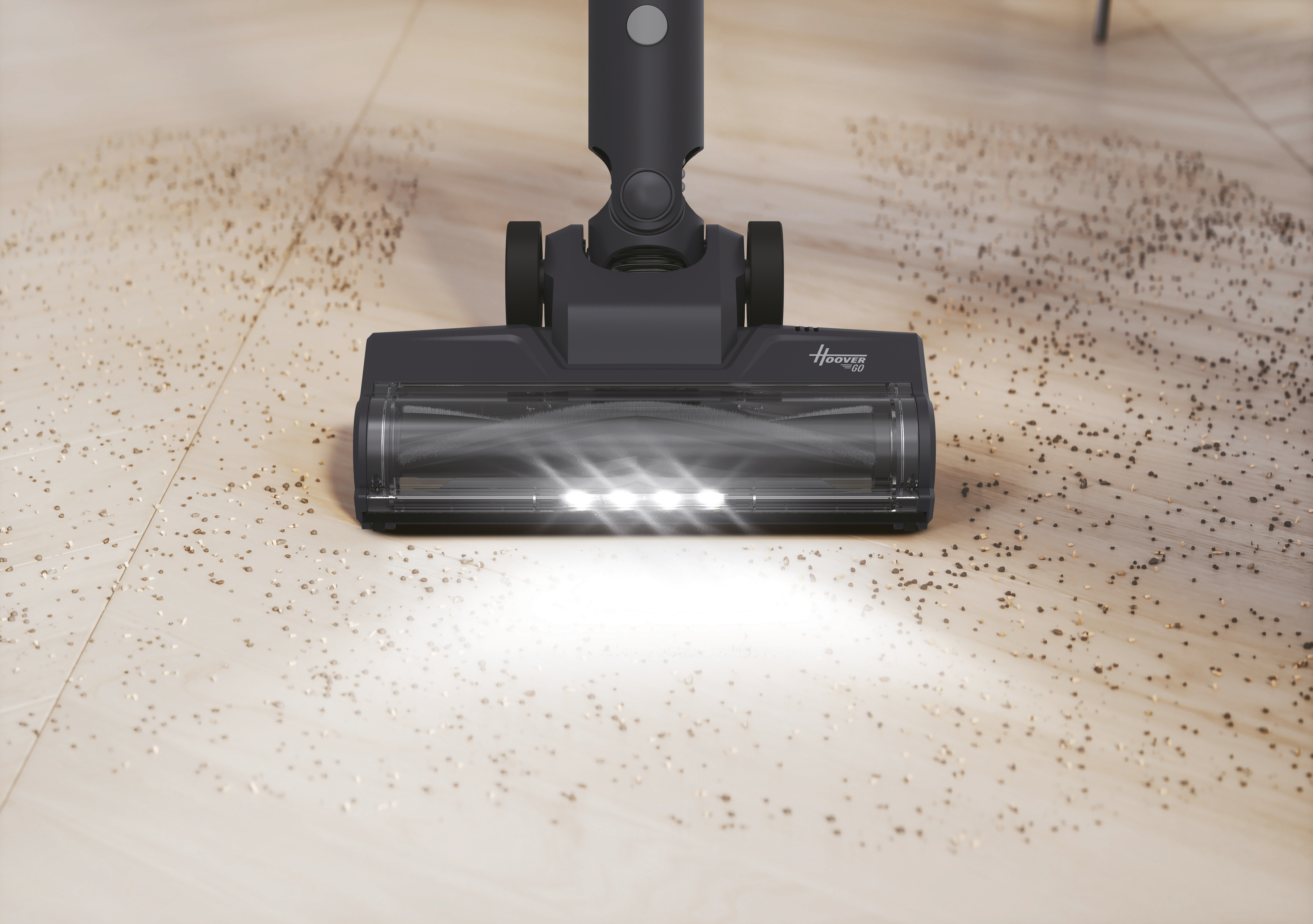 Testina aspirapolvere grigio scuro con luci su pavimento sporco.