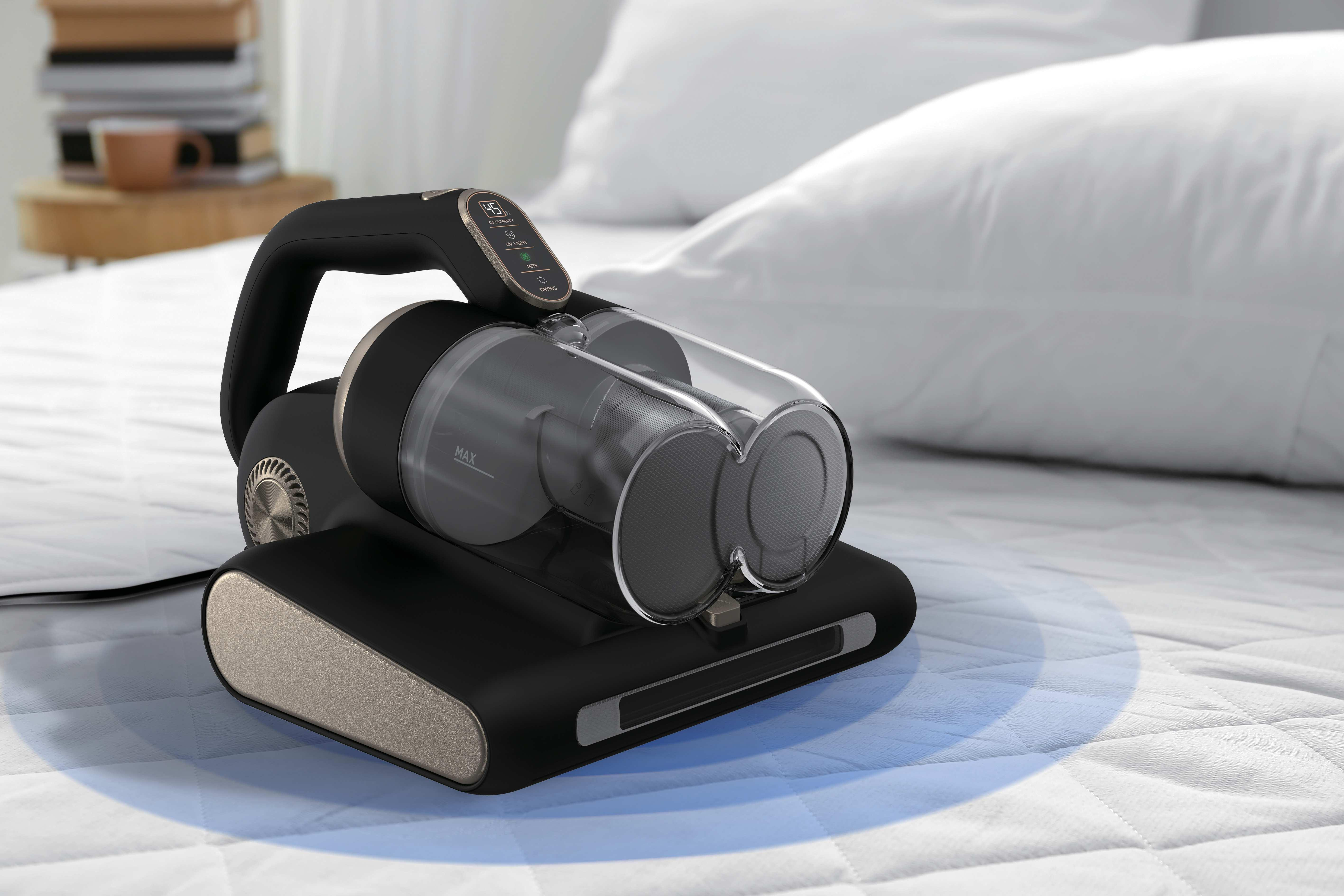 Un aspirapolvere nero poggia su un letto bianco, emettendo un bagliore blu.