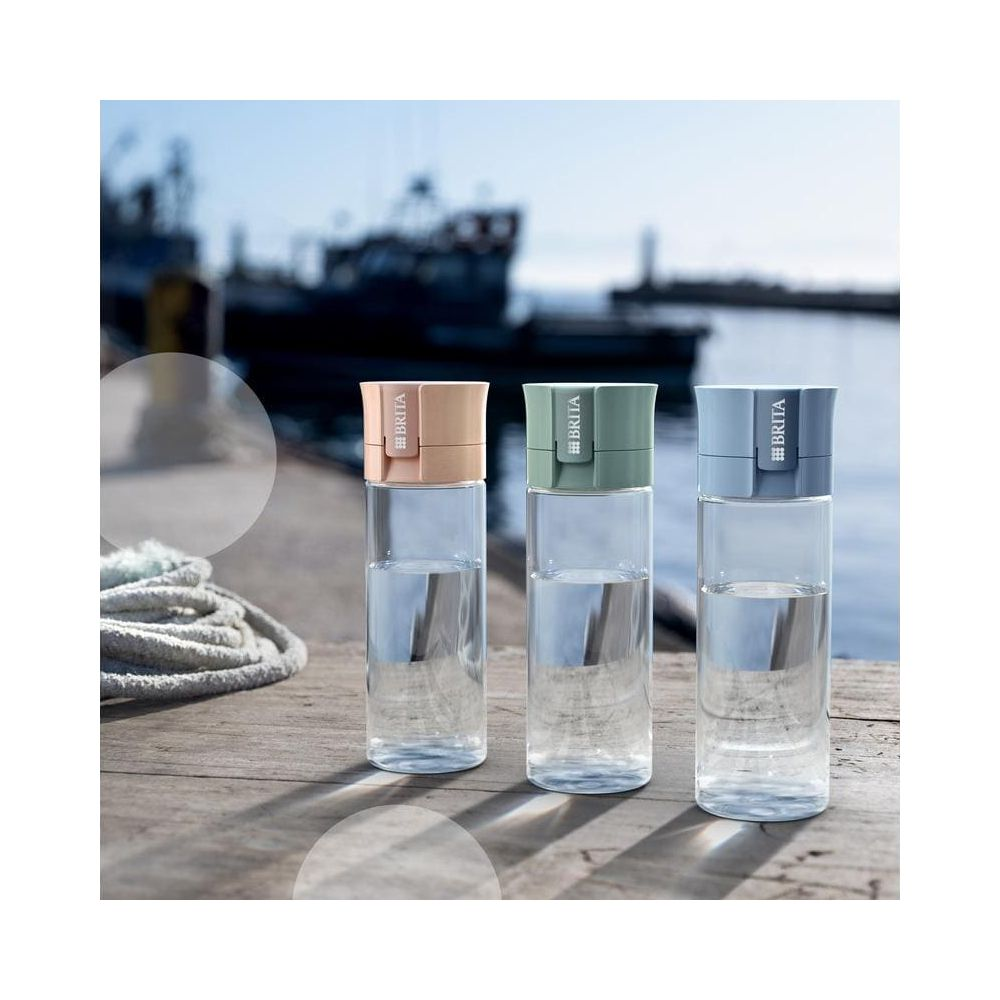 Trzy butelki na wodę Brita z kolorowymi nakrętkami stoją na drewnianym pomoście.