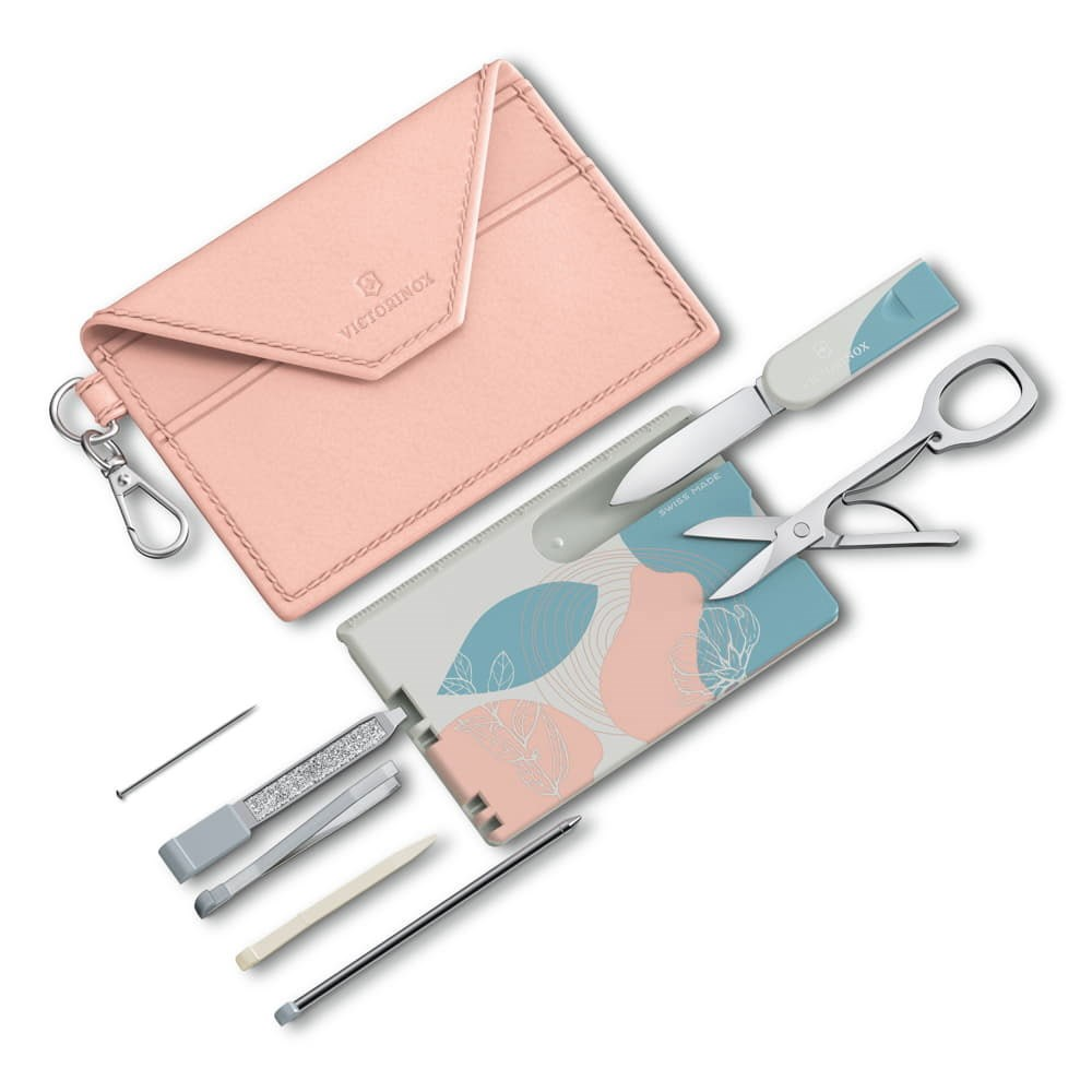 Makas ve bıçaklı bir alet setinin yanında Victorinox logolu pembe bir zarf.