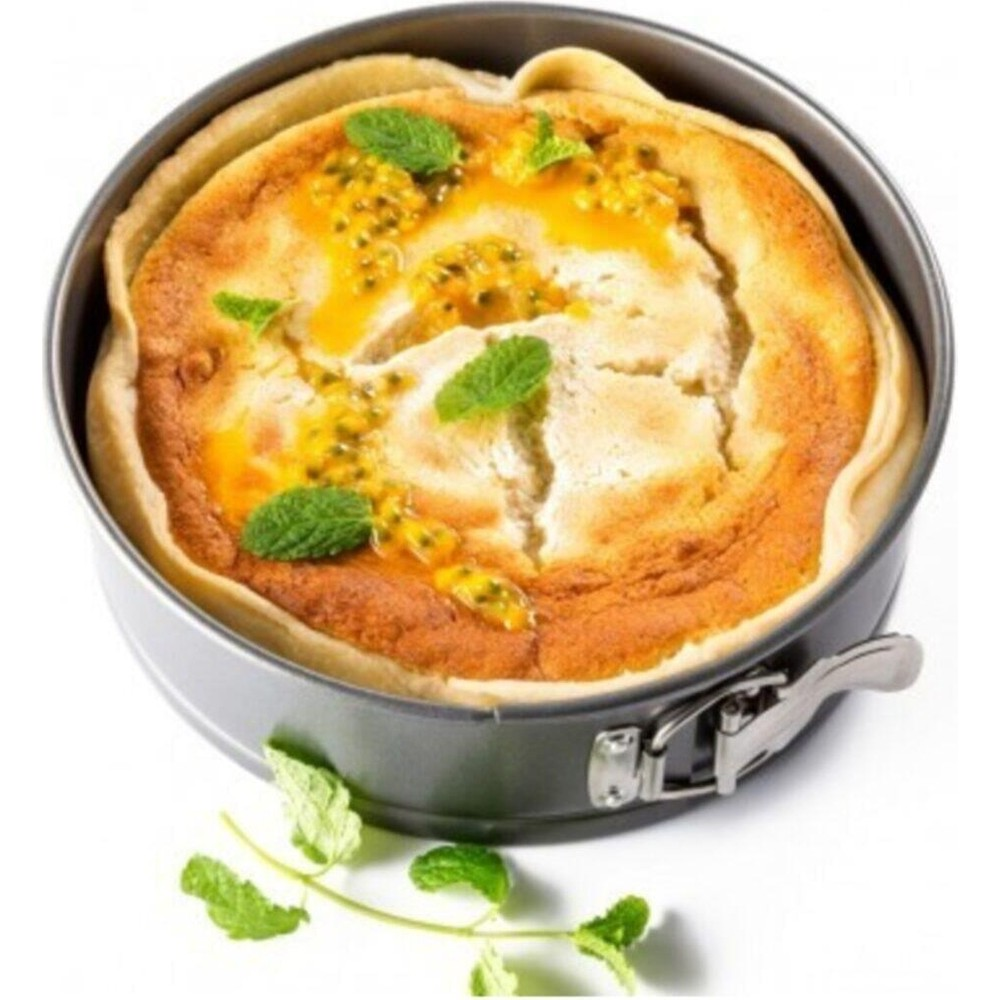 Yuvarlak bir kek kalıbında, nane yapraklarıyla süslenmiş altın rengi çarkıfelek meyveli tart.