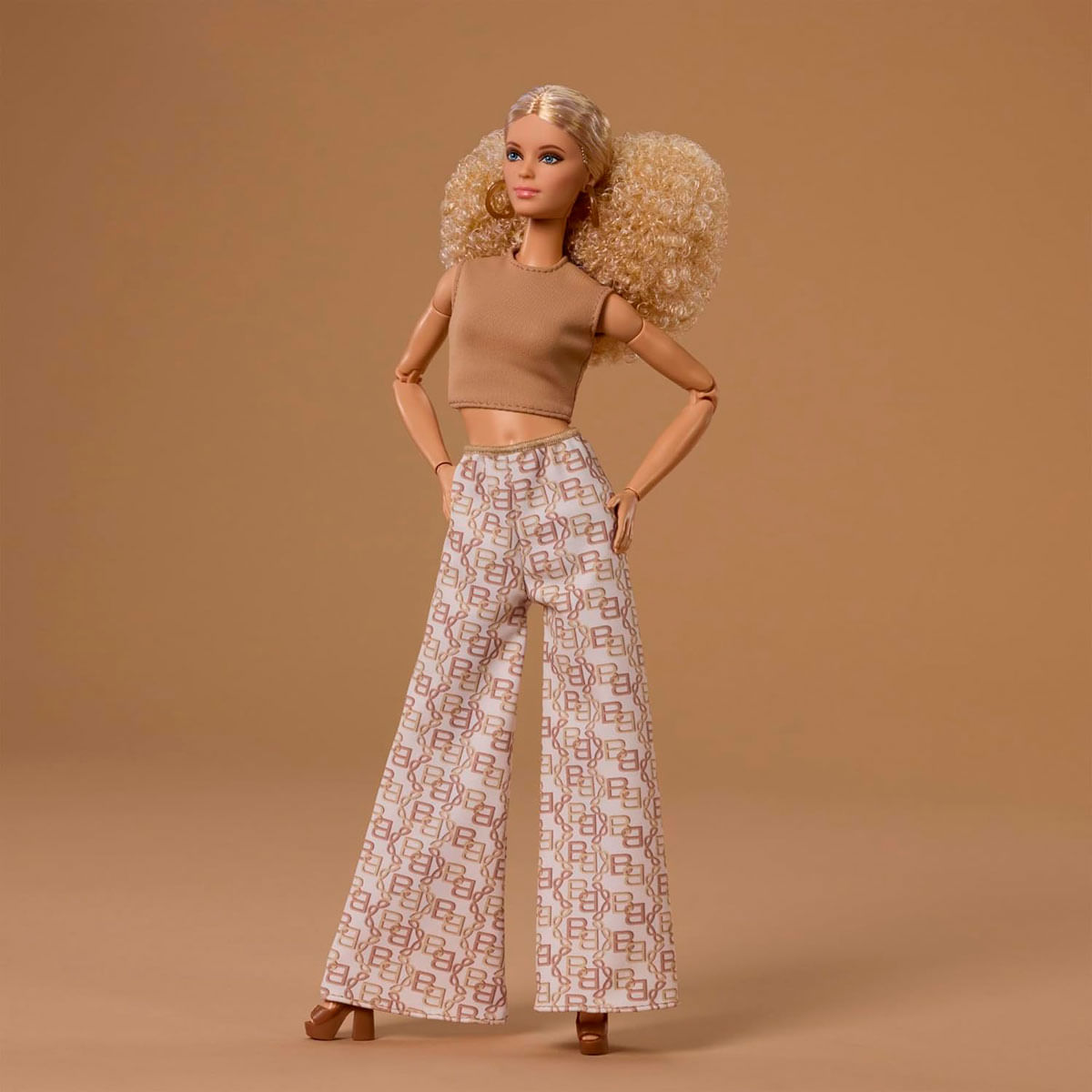 Eine blonde Barbie-Puppe trägt ein braunes Oberteil und eine Hose mit Muster.