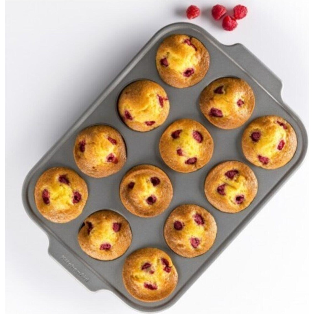 12 adet pişmiş ahududulu muffin içeren bir muffin kalıbı. Üstte serbest ahududular var.