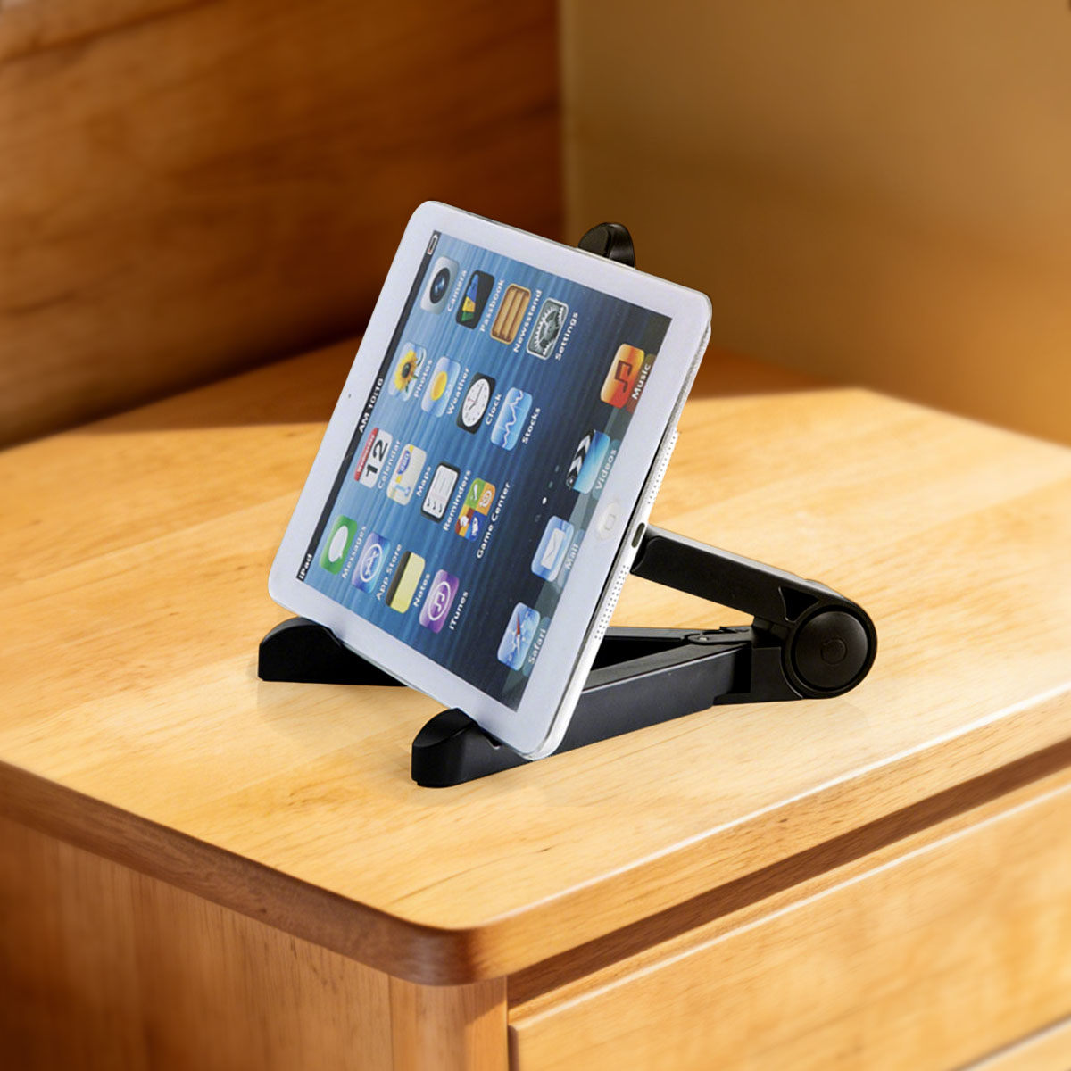 Biały iPad jest wyświetlany na czarnym stojaku na drewnianym stole. Ekran pokazuje ikony aplikacji.